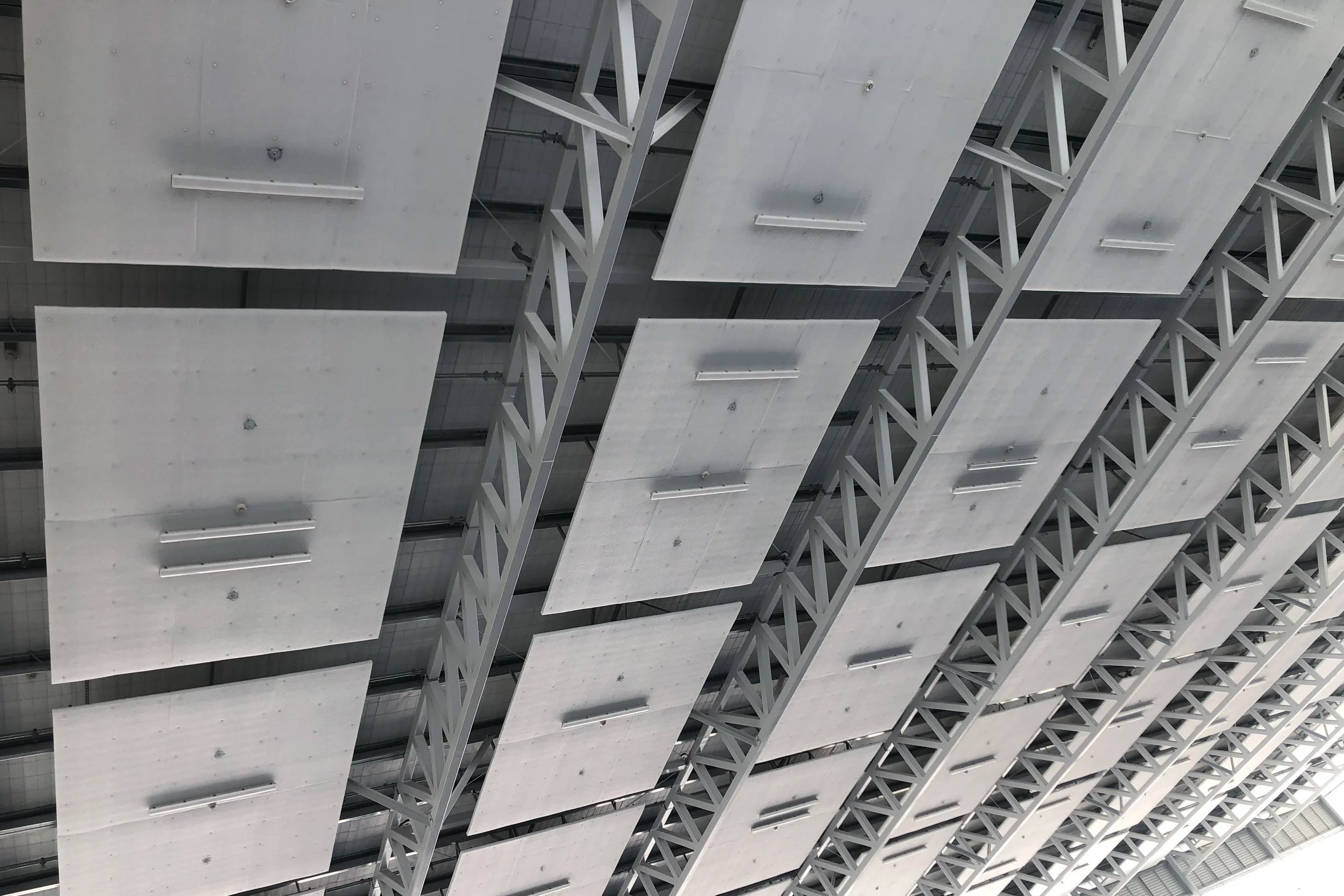 Industriehalle mit Stahlträger-Dachkonstruktion und montierten weissen Akustikpaneelen zwischen den Trägern