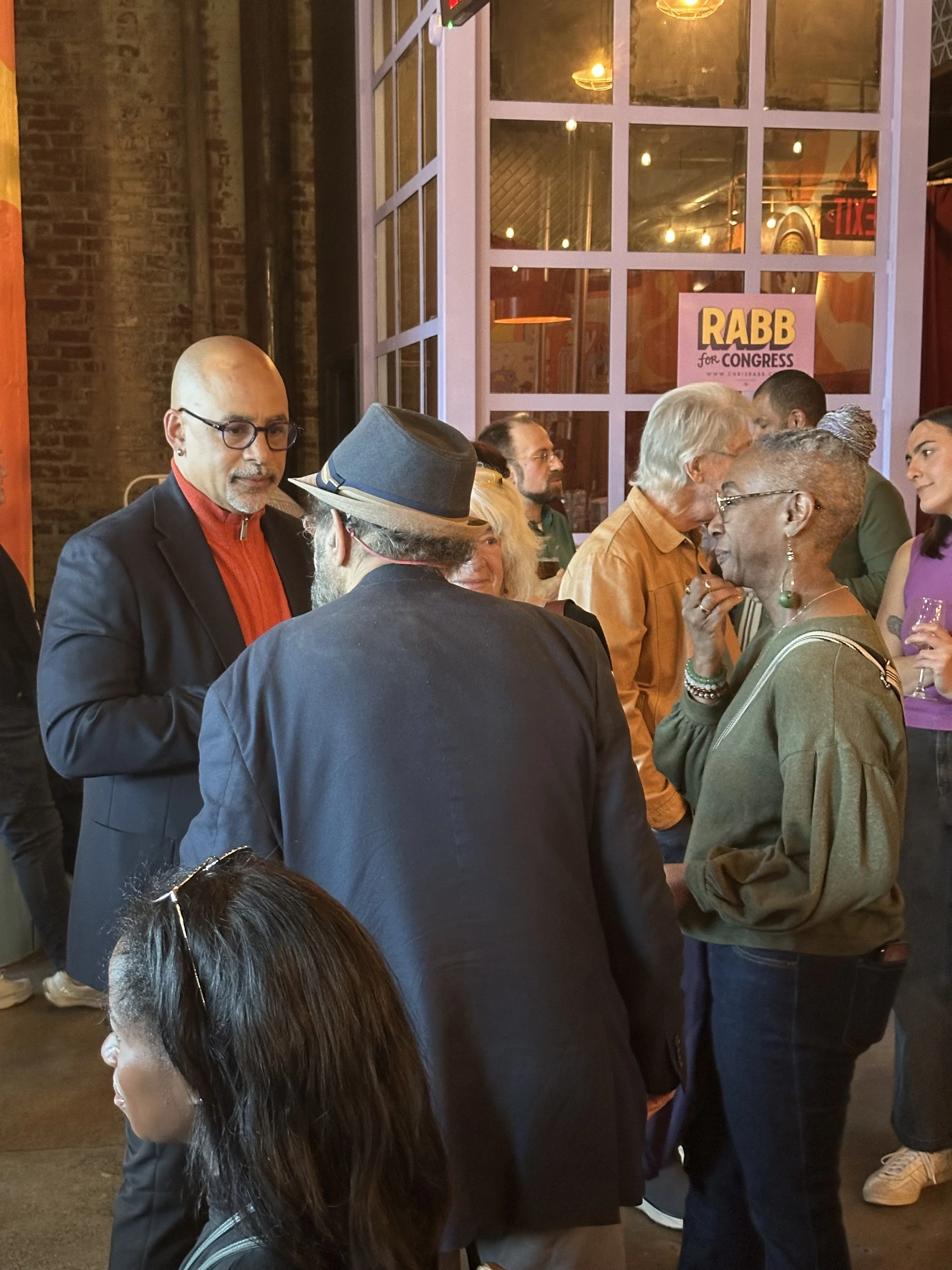 several people gathered inside a bright airy space talking with a person at a community gathering at cerveau