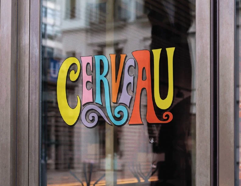 Colorful sign on a glass window spelling 'CERVEAU' with whimsical lettering and bright colors.