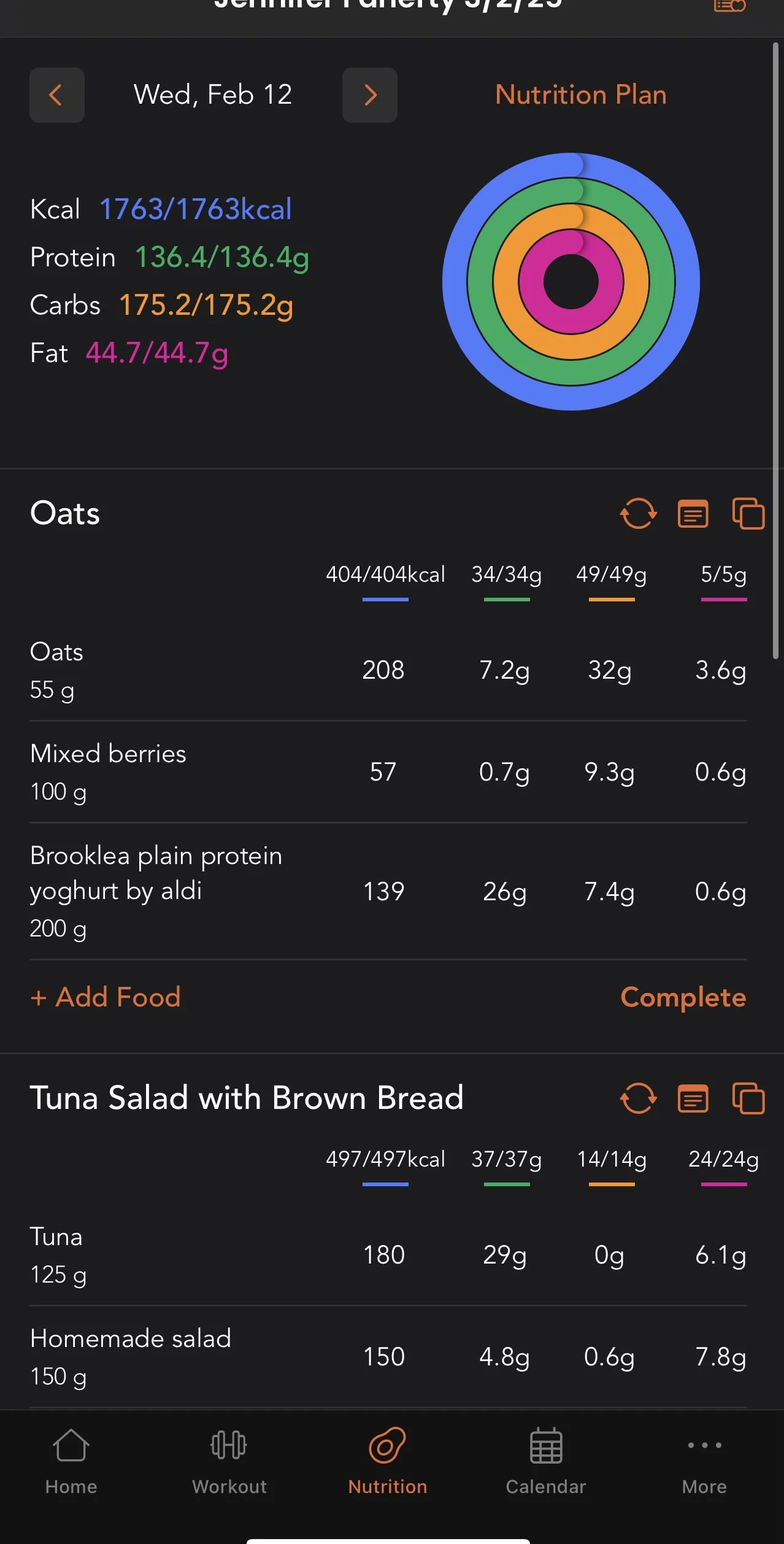 Screenshot of a nutrition app displaying a daily food log. It includes a section labeled 'Oats' with details on 55 grams of oats, mixed berries, and plain Greek yogurt. It also shows a 'Tuna Salad with Brown Bread' section with 125 grams of tuna and 150 grams of homemade salad. Nutritional information like calories, protein, carbs, and fat for both meals is displayed, along with a colorful circular diagram representing daily nutrient intake.