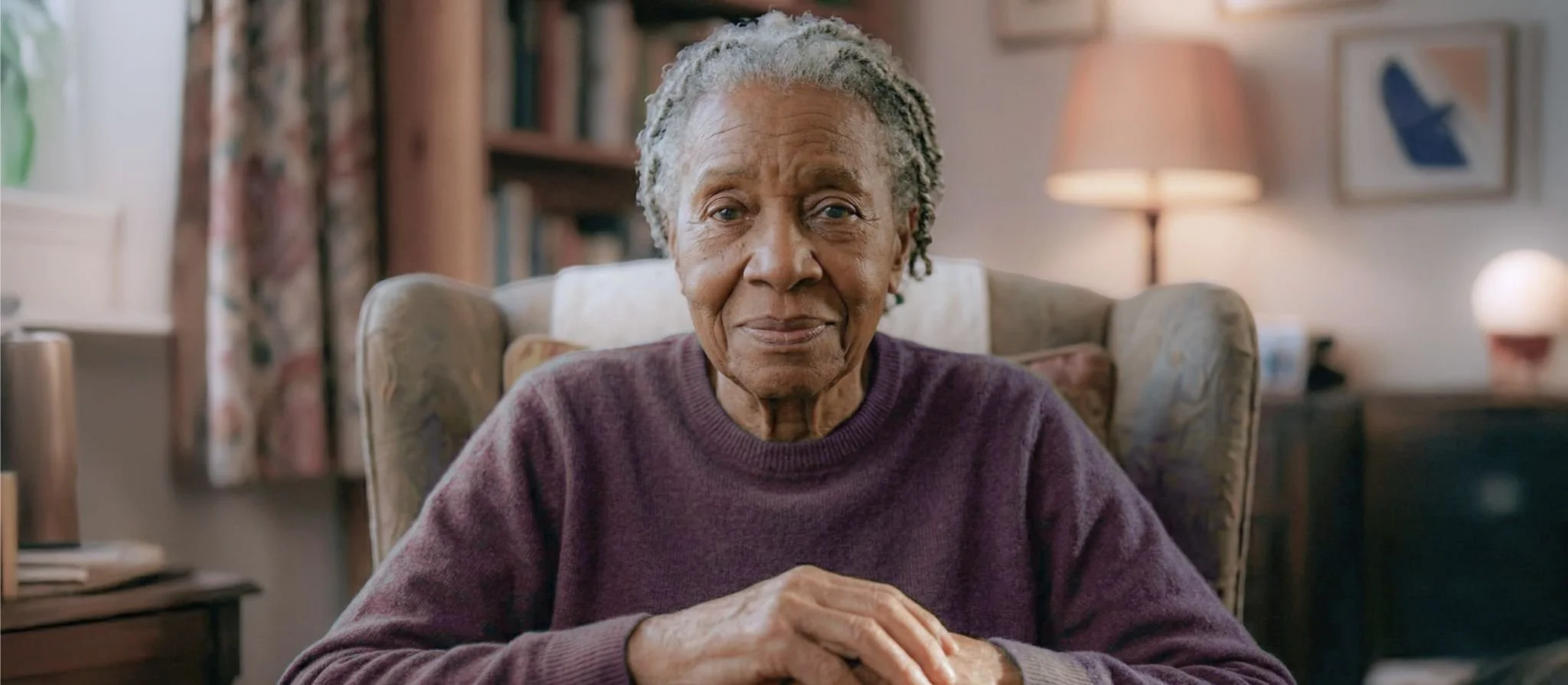 An elderly woman at home with a warm, hopeful expression, looking toward a future where the right care and support reaches everyone at the right time.
