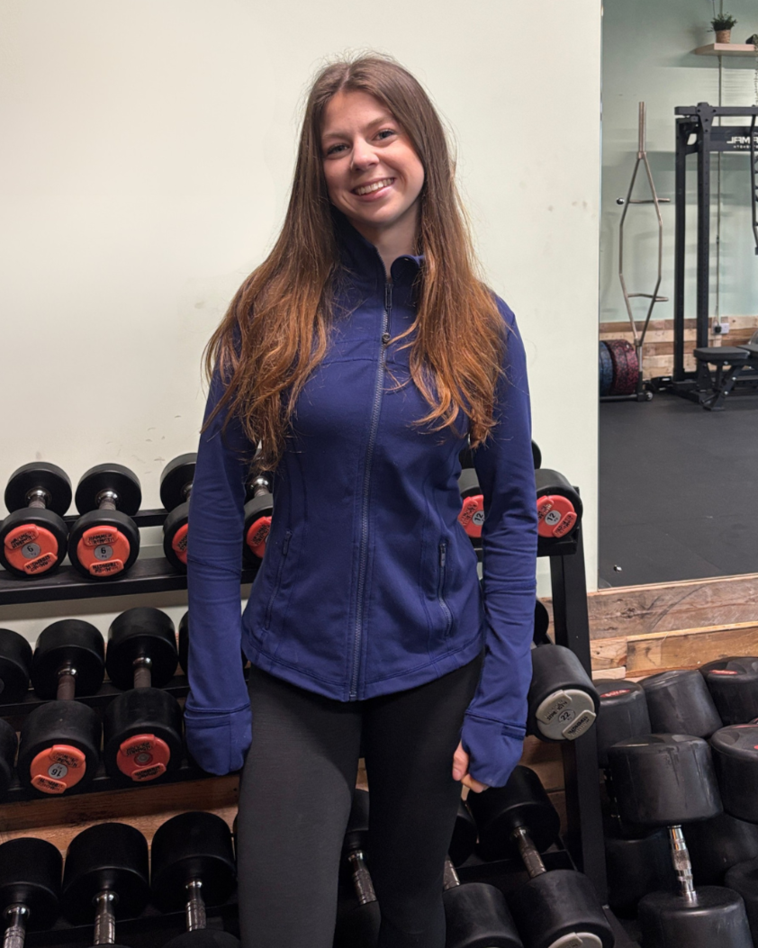 Annie Walker, Sheffield-based personal trainer and Pilates instructor, standing in a gym next to dumbbells