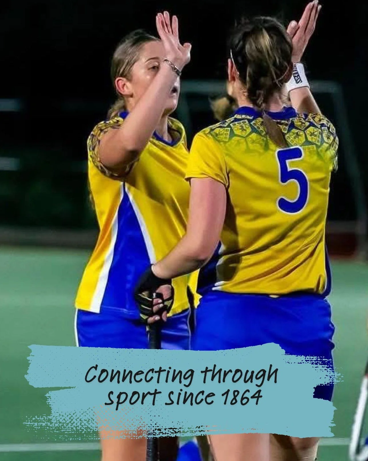 Two female field hockey players in yellow and blue uniforms sharing a high-five on the field at night. One has the number 5 on her jersey. A caption reads 'Connecting through sport since 1864'.