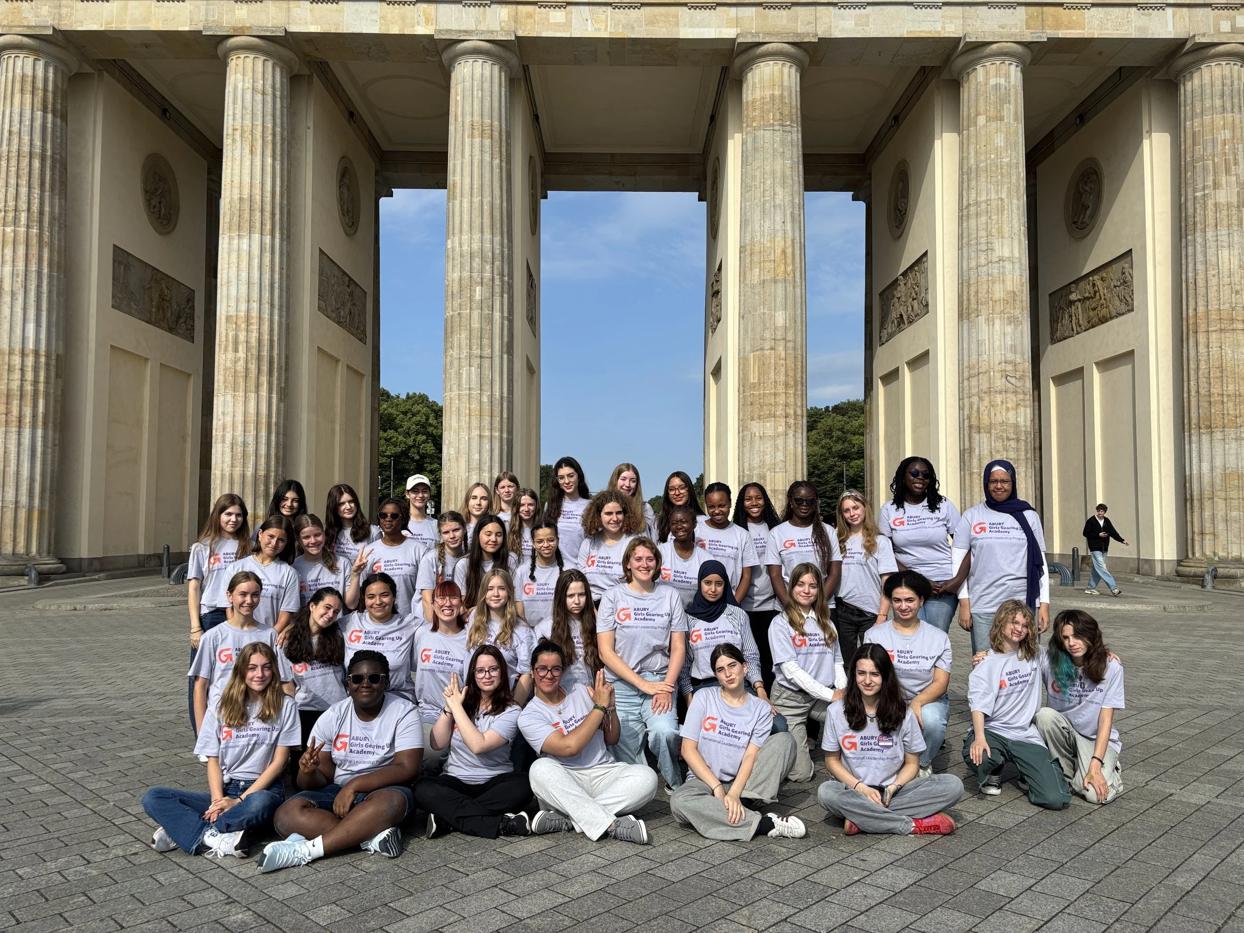 Gruppenfoto junger Frauen und Mädchen vor dem Brandenburger Tor in Berlin, alle tragen T-Shirts mit dem Logo 'Girls Gearing Up Academy'.