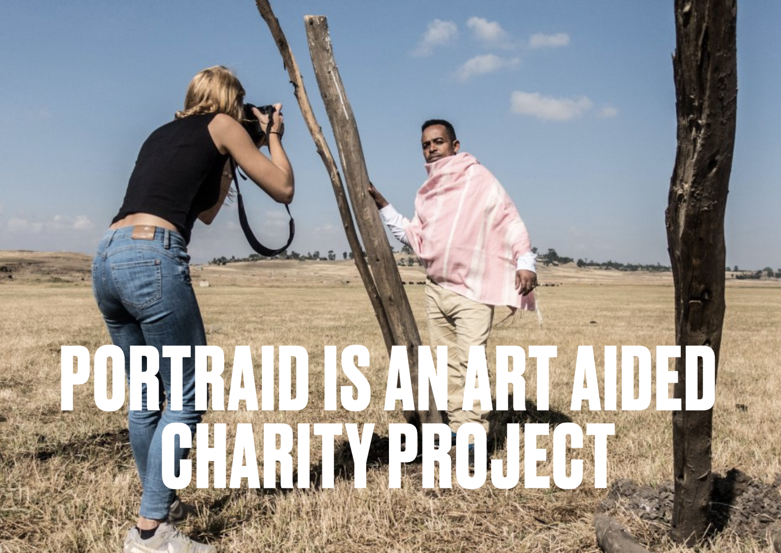 Ein Fotograf macht ein Porträt eines Mannes, der in einer offenen, ländlichen Landschaft steht, während die Frau ein Fotoshooting durchführt.