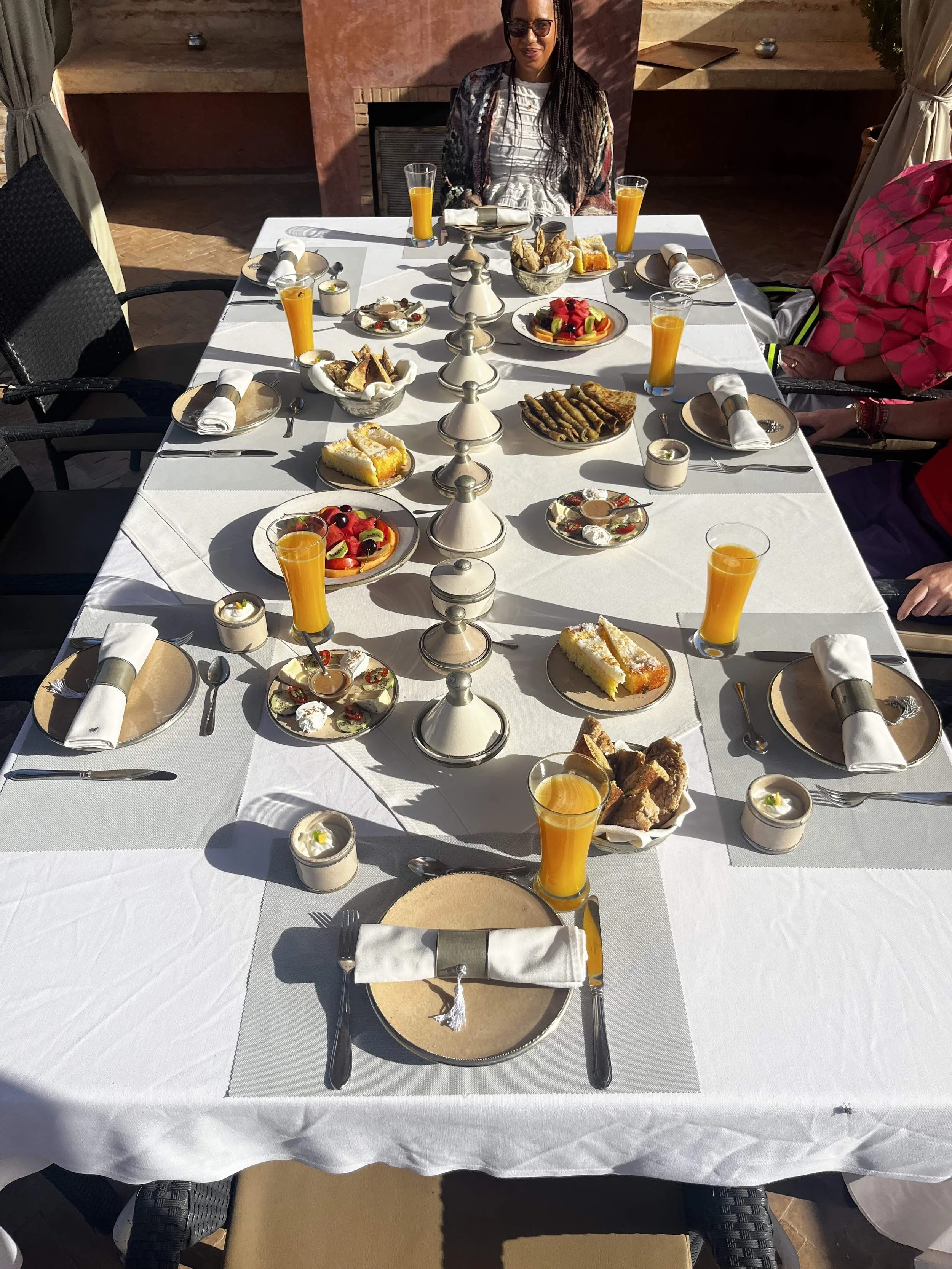 Ein verführerischer gedeckter Frühstückstisch mit Brot, Orangensaft, Kuchen und Obst für acht Menschen