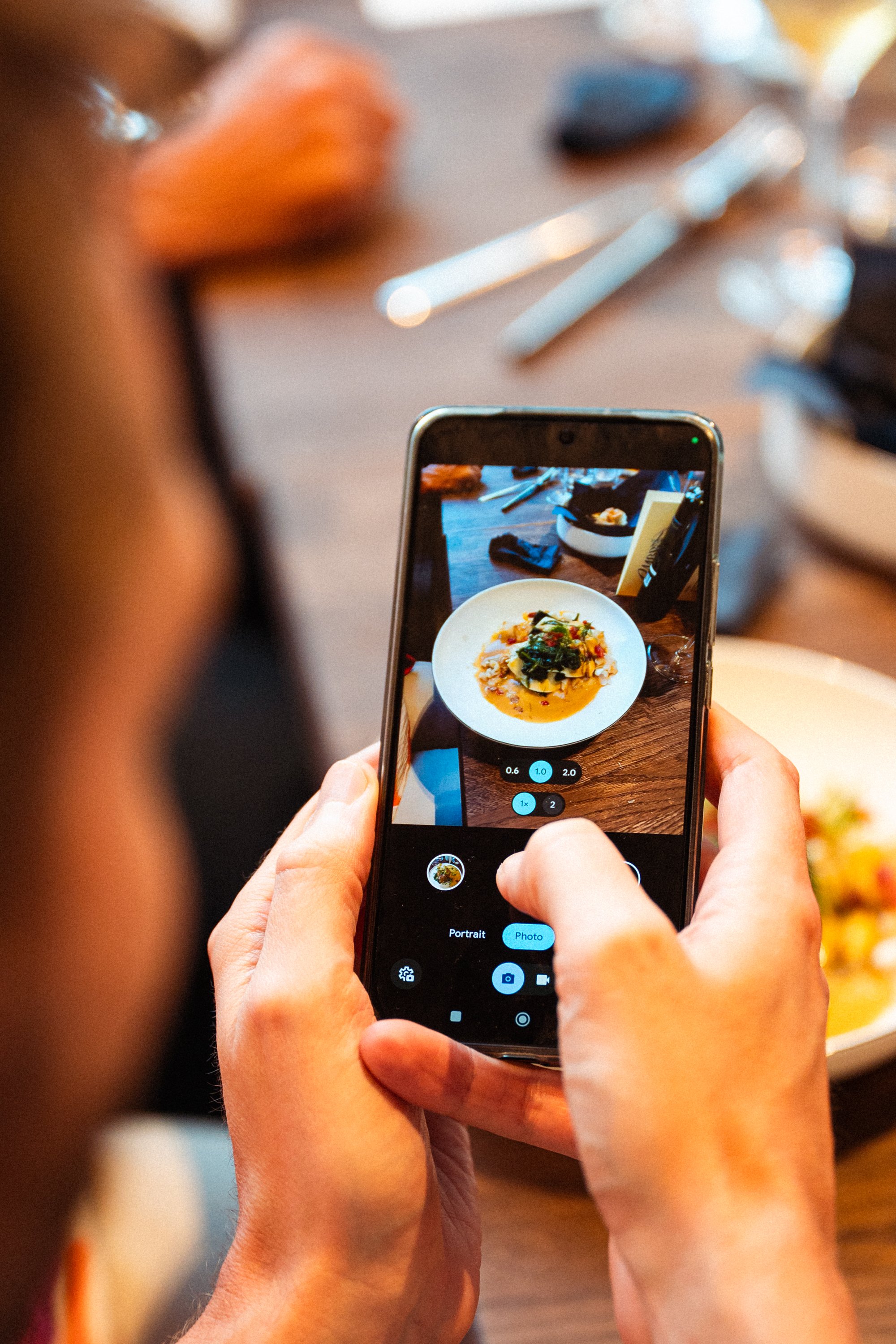 Persoon neemt een foto van een bord eten met een smartphone in een restaurant.