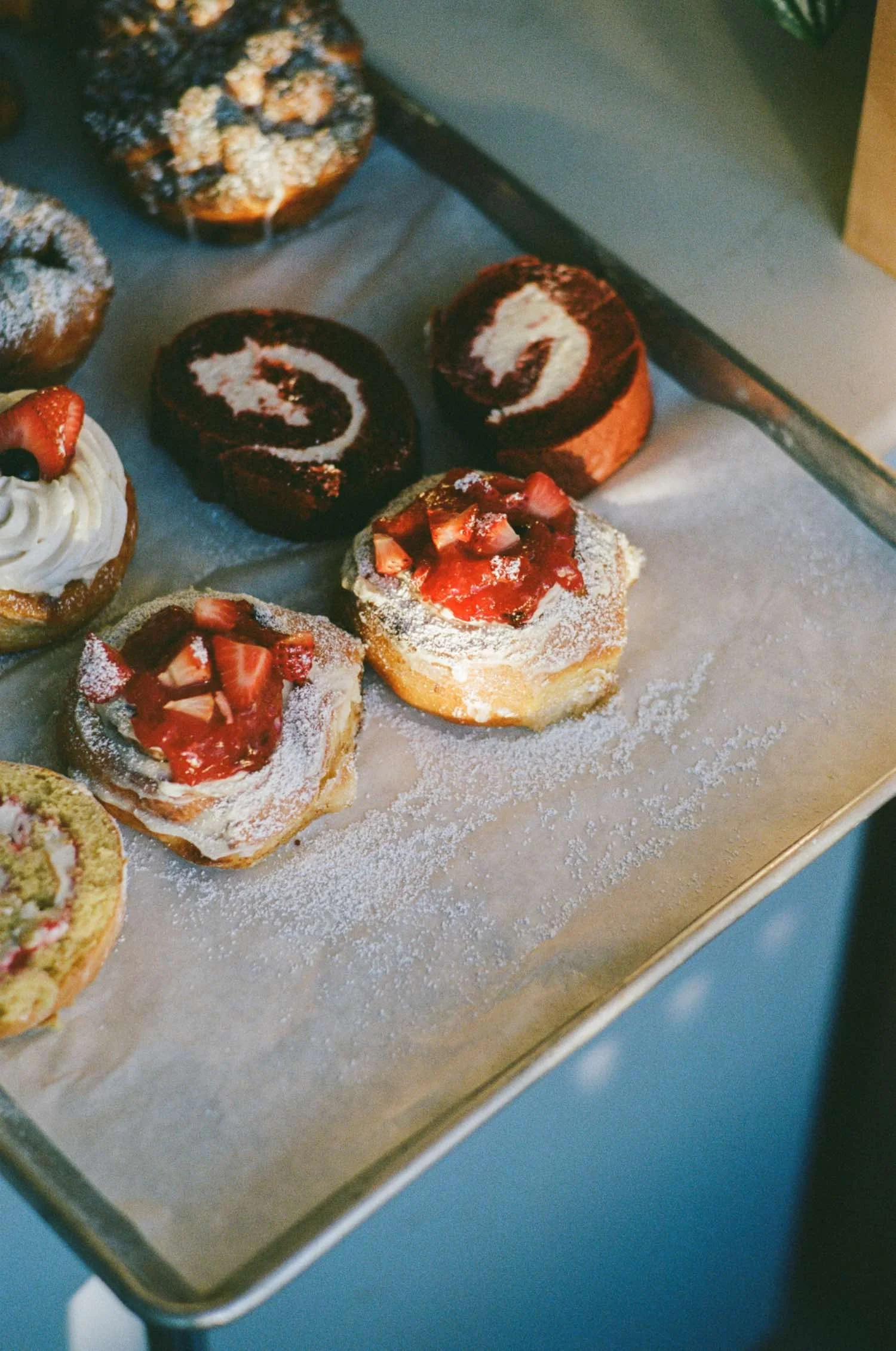 Assorted mini desserts on a tray, including mini strawberry-topped cakes and rolled chocolate cakes with cream filling.