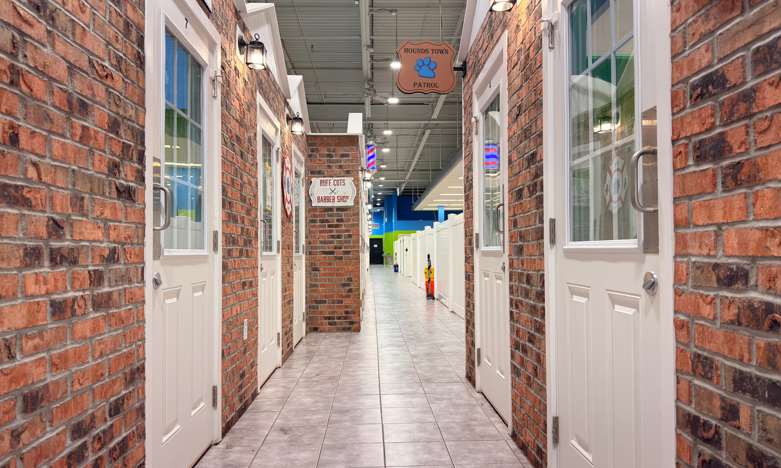 Design construction in ohio creating interior hallway with brick walls, white doors, and signage in a pet boarding or daycare facility.