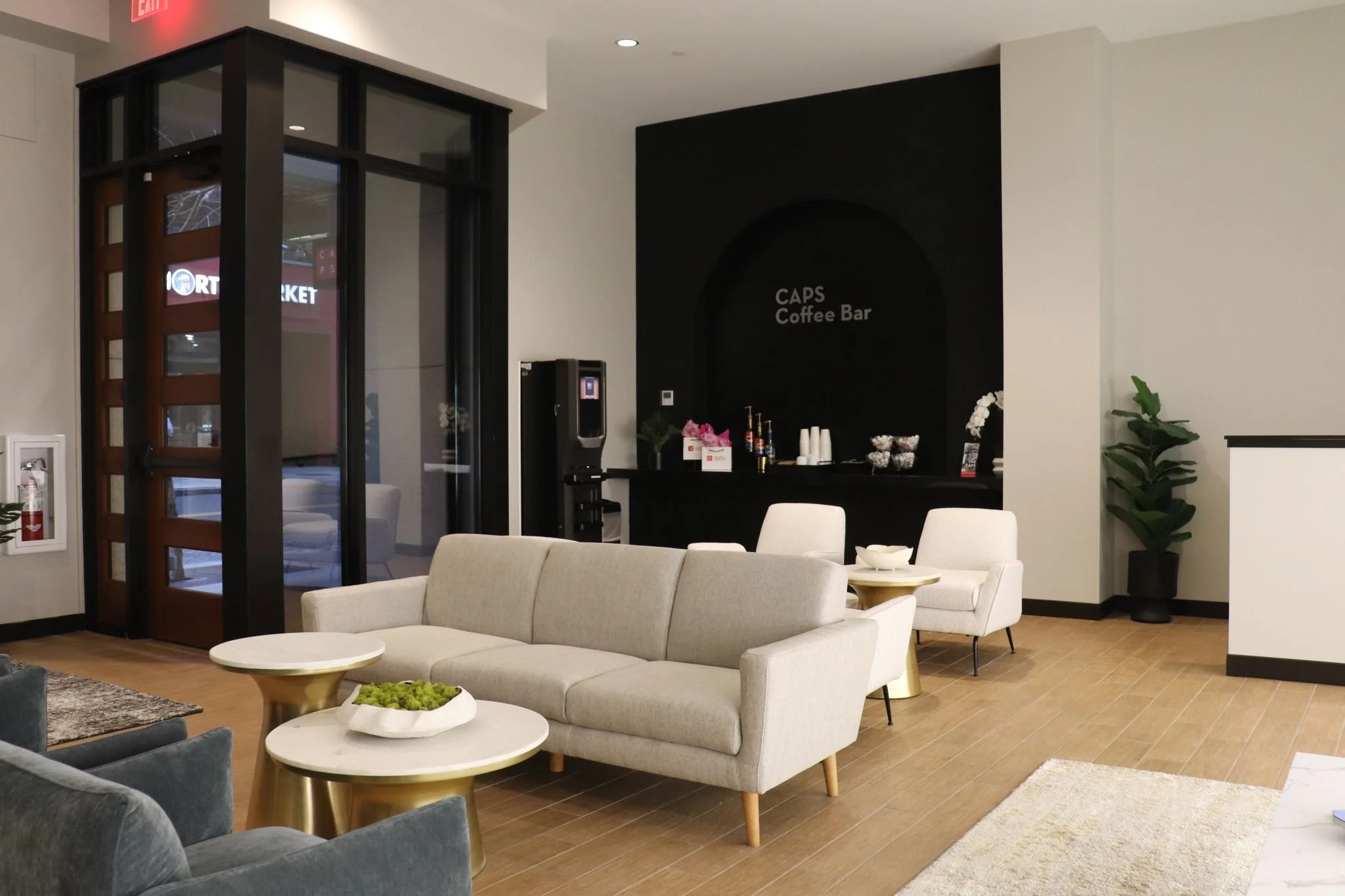 Modern lobby area with light sofas, coffee tables, and a coffee bar labeled "CAPS Coffee Bar" in the background made by Central Ohio general contractors.
