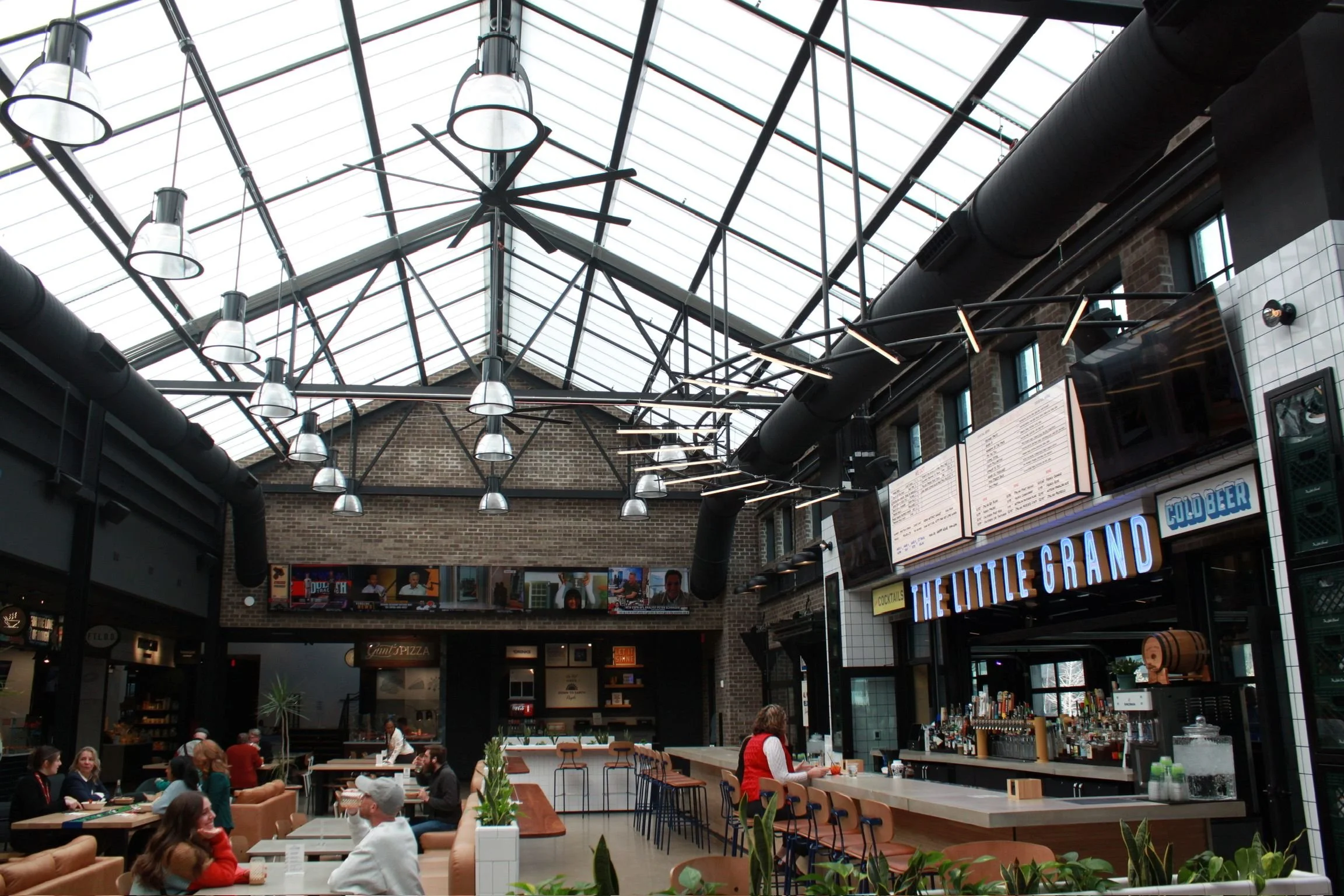 An image of the common area in the Little Grand Market showcasing the glass ceiling and chairs and tables.