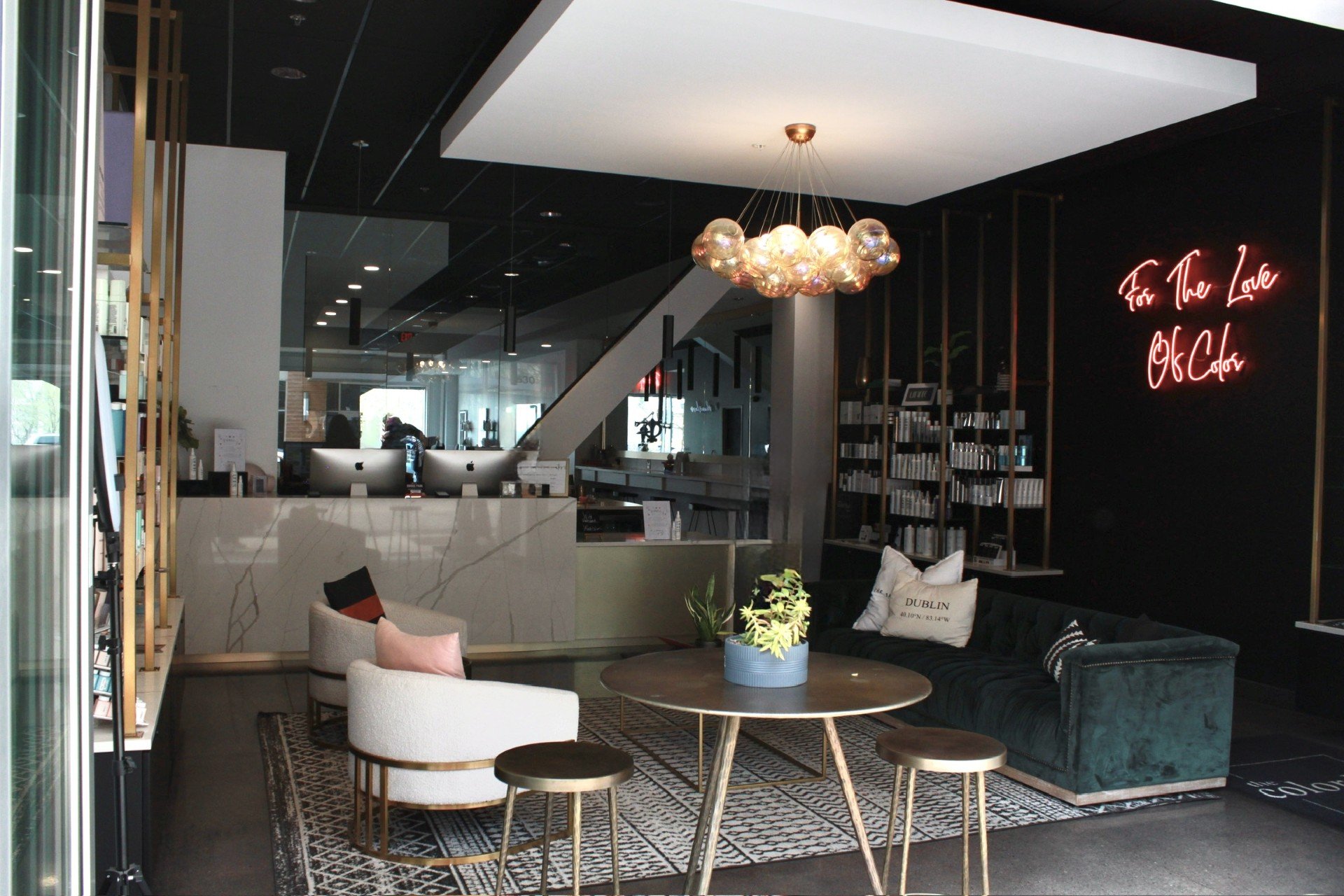 Modern reception area with a front desk, seating, round tables, bookshelves, and a neon sign on a dark wall created by a women-owned commercial construction firm in Central Ohio.