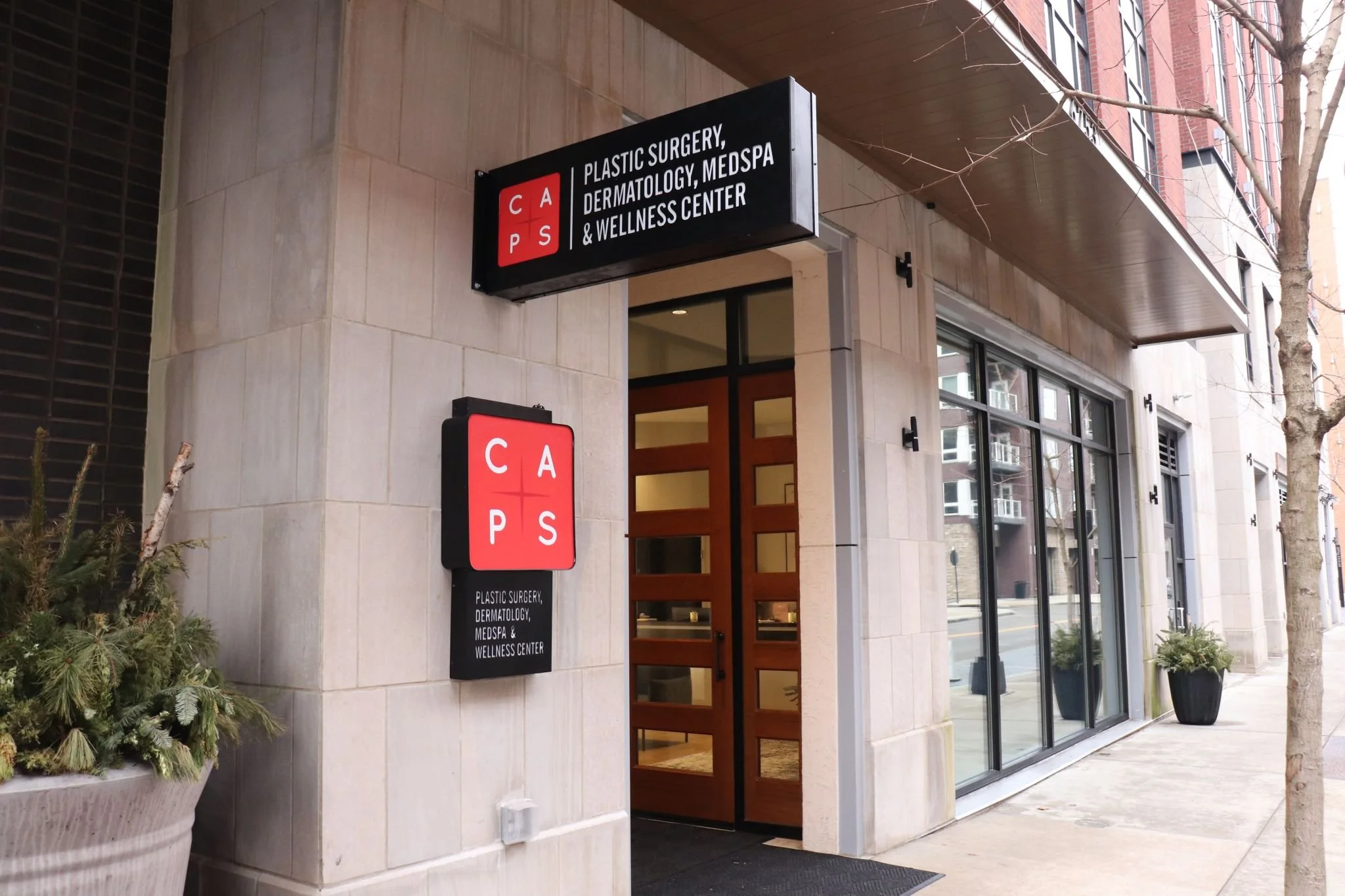 Entrance design to CAPS Plastic Surgery, Dermatology, MedSpa &amp; Wellness Center with clear signage on a city sidewalk.