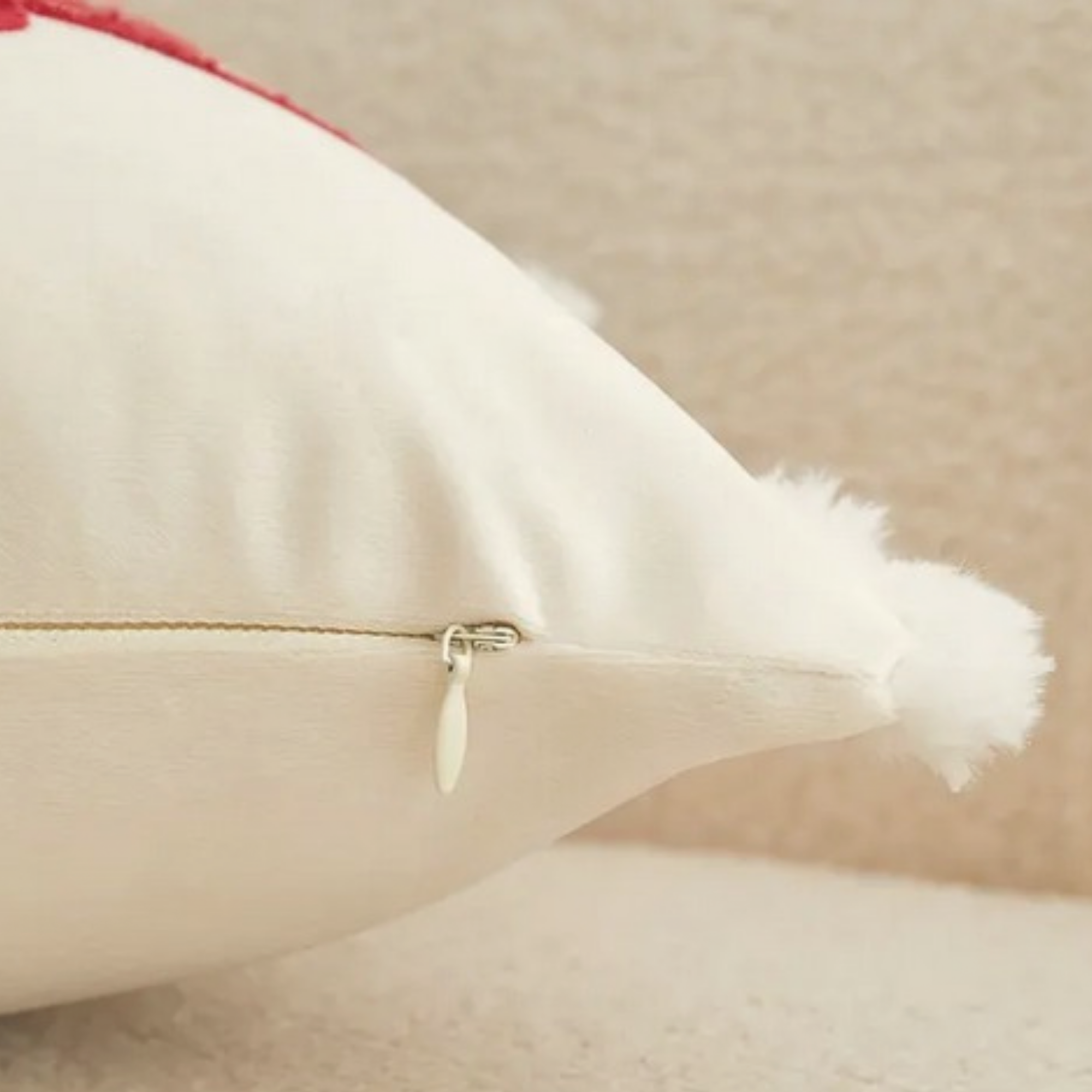 Back detail of cream Christmas cushion showing concealed zip closure and pom pom trim