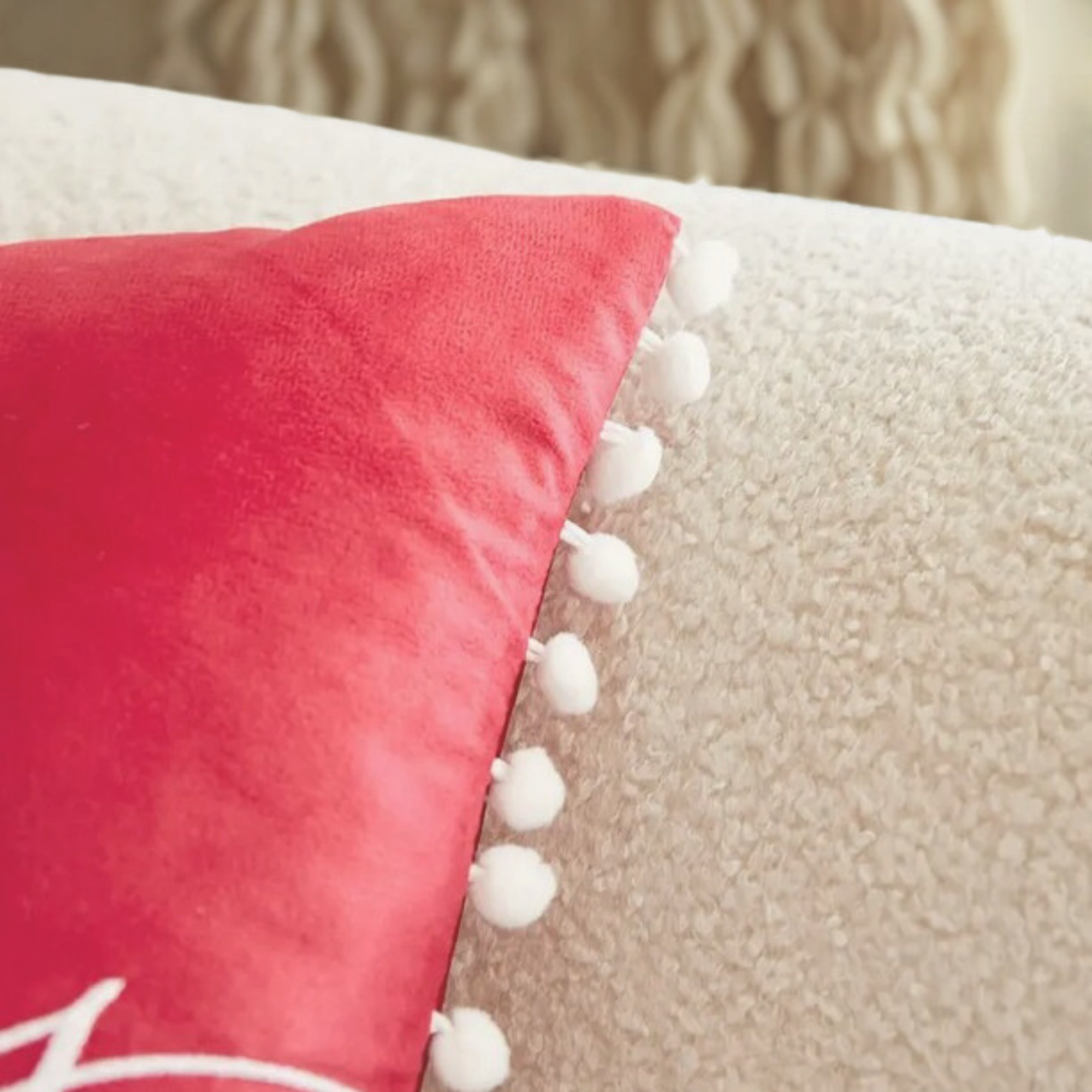 Close-up detail of red Merry Christmas cushion with white pom pom trim