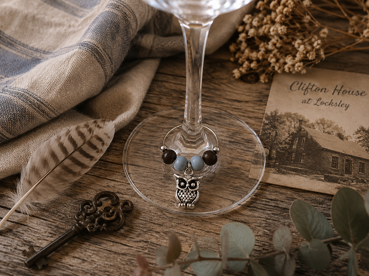 Feather & Sky wine charm duo with silver owl charms and soft neutral beads displayed on a wine glass with heritage inspired styling