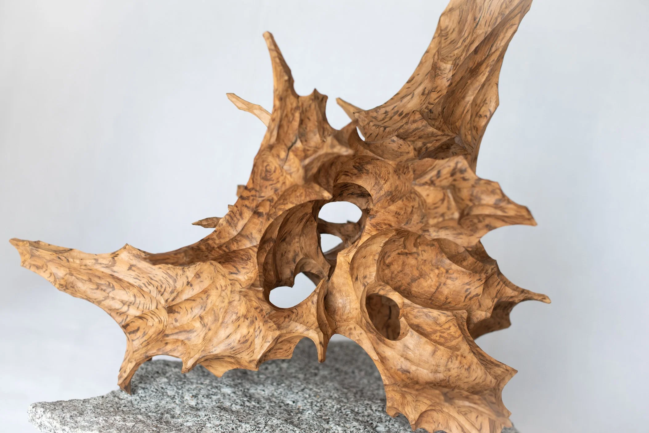 A wooden sculpture of a skull with engraved details on a textured rock surface.