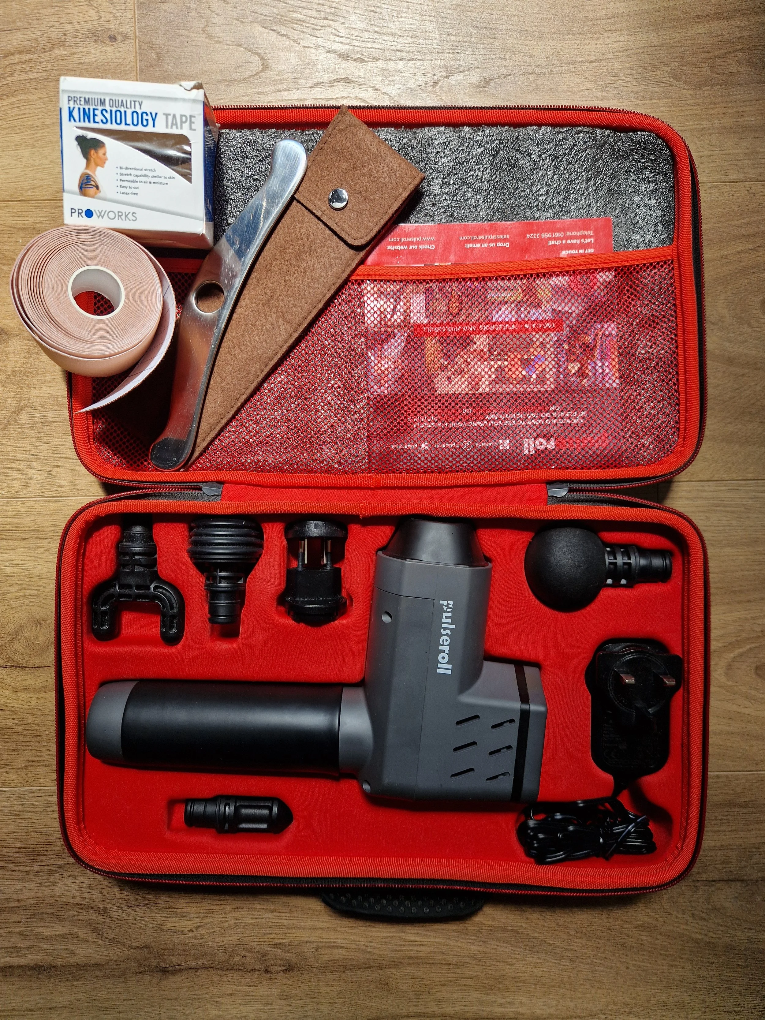 A collection of additional tools used for massage treatments, kinesio tape, massage gun and gua sha tool