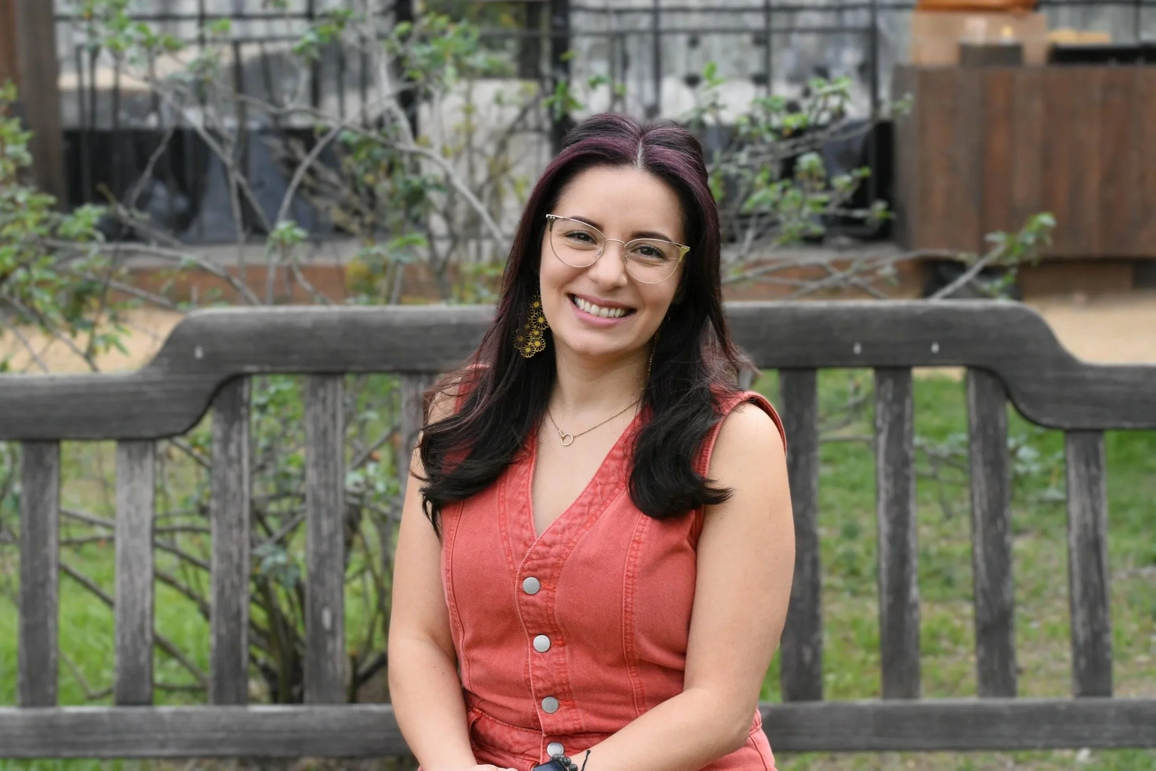 Therapist Lili smiling while seated on bench outside with greenery