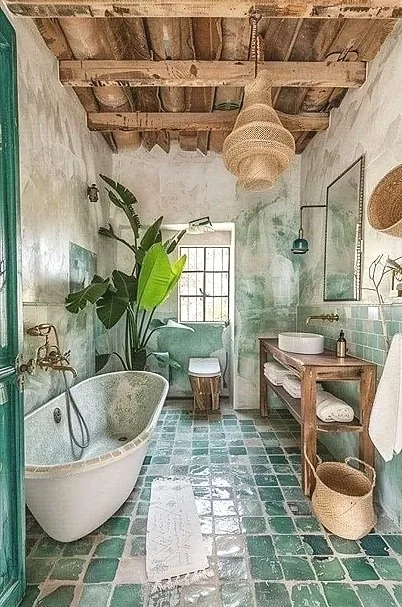 Salle de bain rustique avec baignoire en standalone, grande plante verte, fenêtre, lavabo en bois, sols en carreaux verts, paroi en carreaux turquoise, éclairage suspendu, rangement avec serviettes, panier en osier.