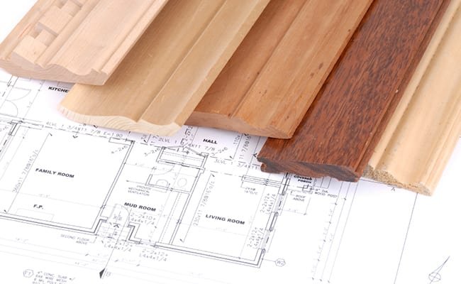 Sample of hardwood flooring planks placed on architectural blueprint floor plan.