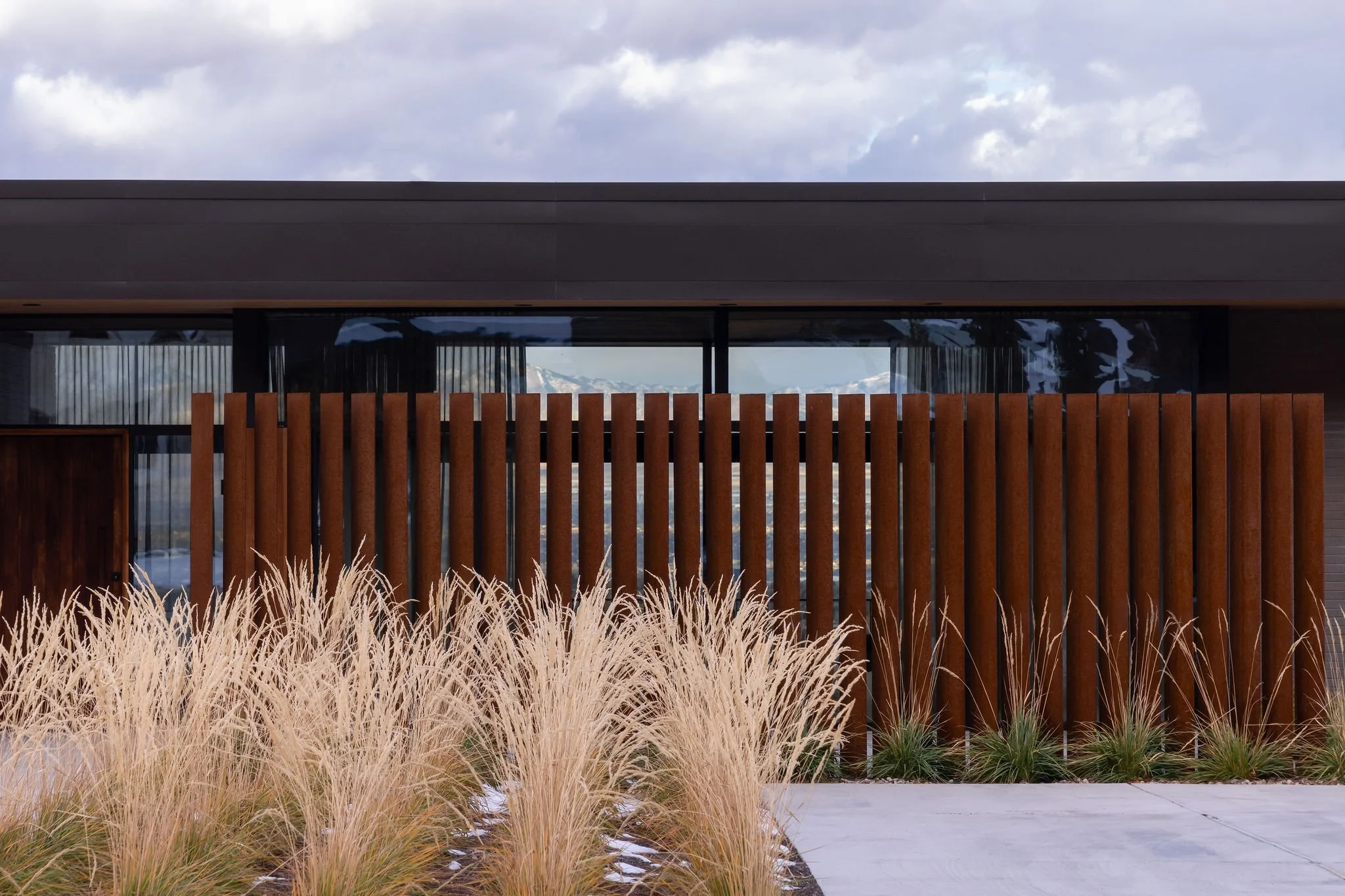 Weathered-steel slat screen and ornamental grasses in front of a modern home, Giverny, Cottonwood Heights, Utah.
