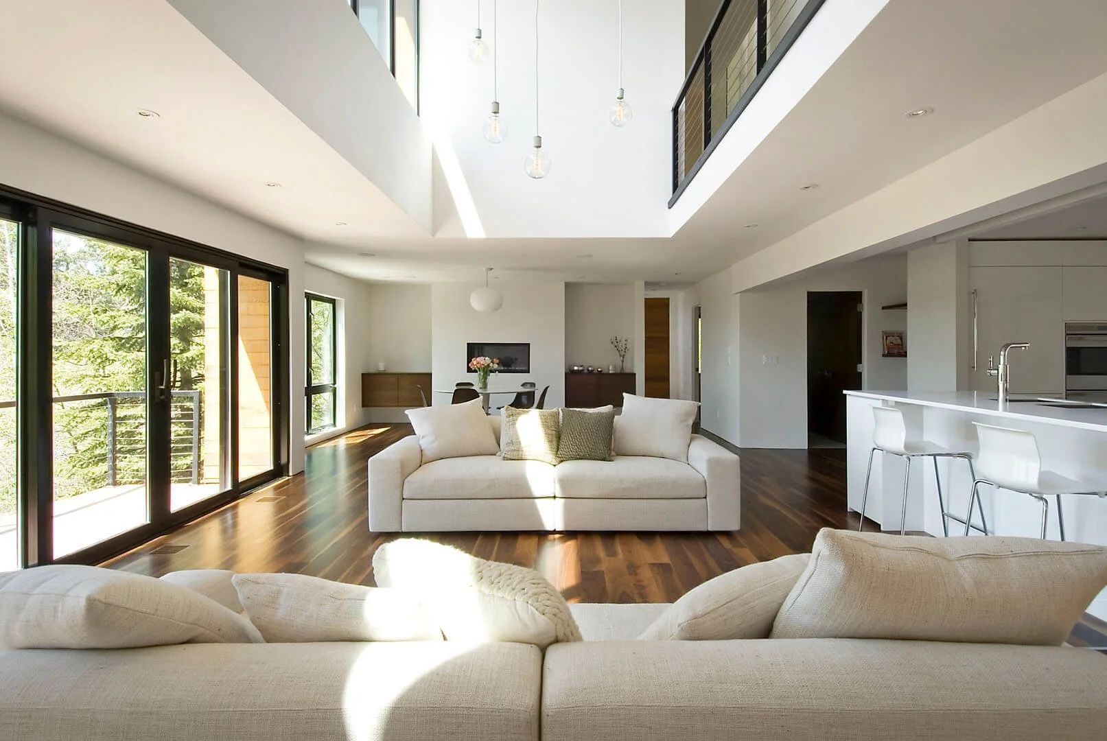 Bright open-plan living room with a double-height ceiling and walls of glass to the trees, Kristianna, Salt Lake City, Utah.