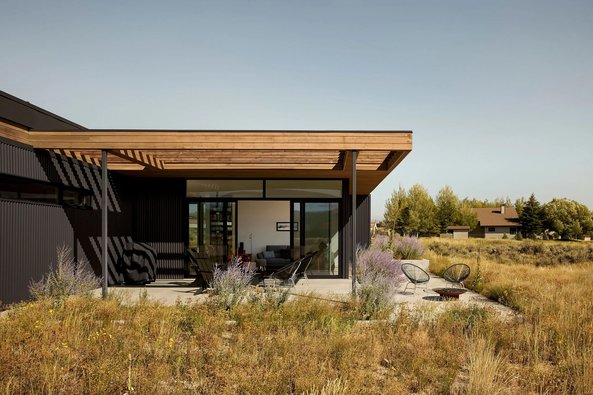 Metal-clad single-level home with a wood-soffit overhang and a wildflower meadow patio, Silver Creek, Park City, Utah.