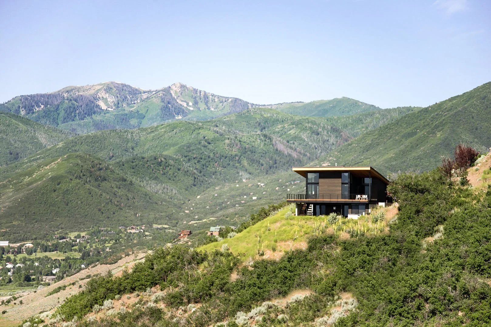 Modern home perched on a green hillside above the Heber Valley with mountain views, Interlaken, Midway, Utah.