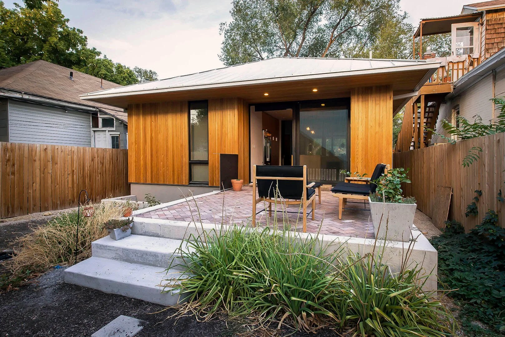 Cedar-clad accessory dwelling unit with a brick patio and landscaped yard, Talvy, Salt Lake City, Utah.