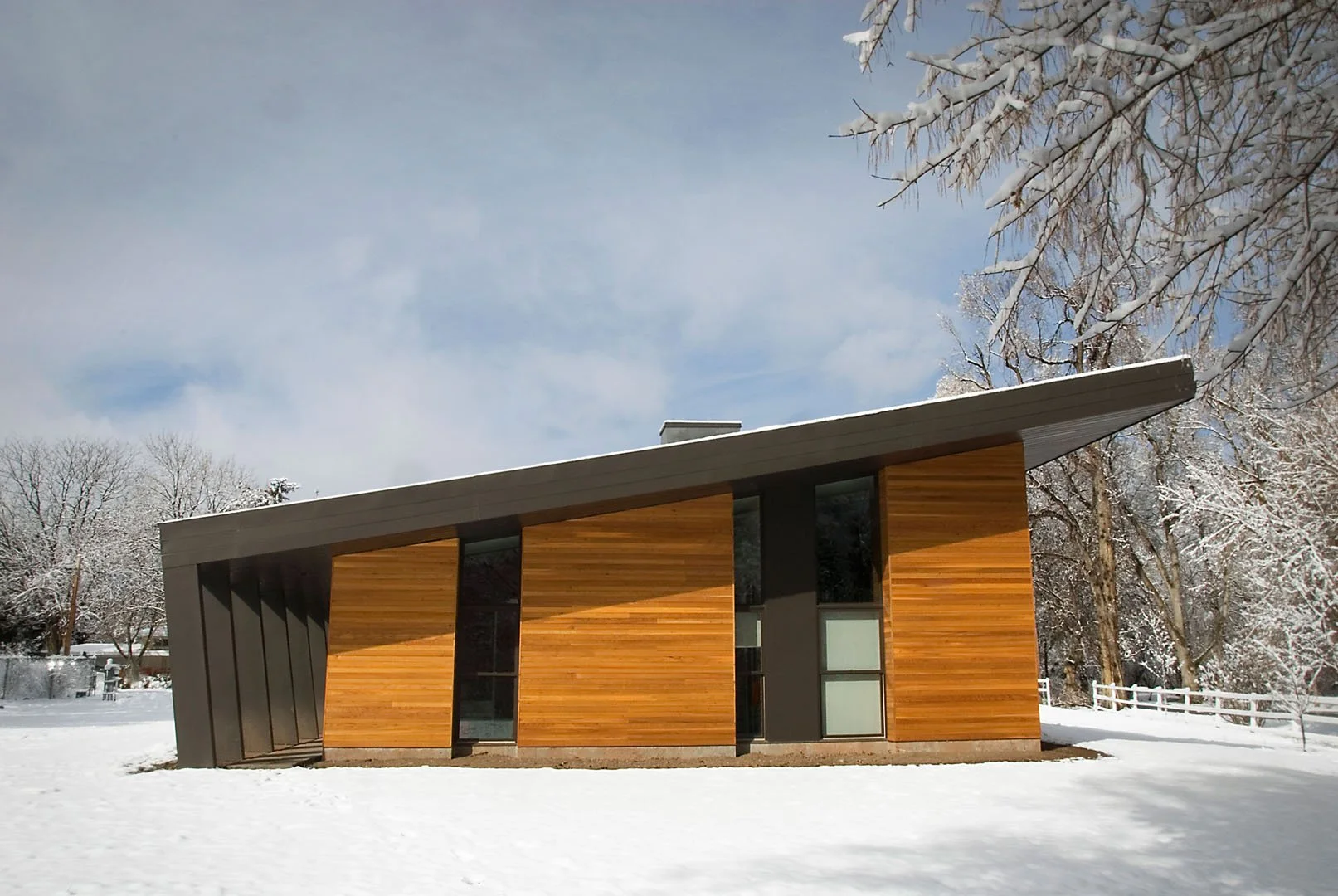 Modern home with cedar cladding and a sweeping single-slope roof in winter, Pasture, Holladay, Utah.