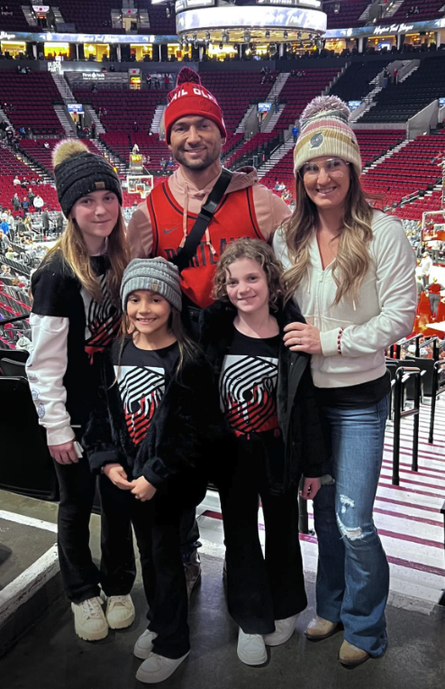 A family of five posing for a photo at a basketball game in an indoor arena, wearing winter clothing and face paint with the Chicago Bulls logo.