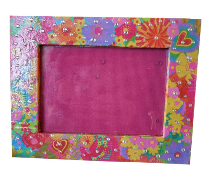Colourful picture frame decorated with pink, yellow, and purple flowers, rhinestones, rainbow, and heart shapes, surrounding a pink cardboard background.