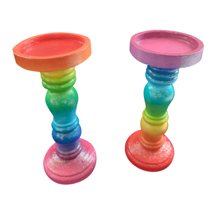 Colorful rainbow-colored candlesticks with round bases and tapered stems.
