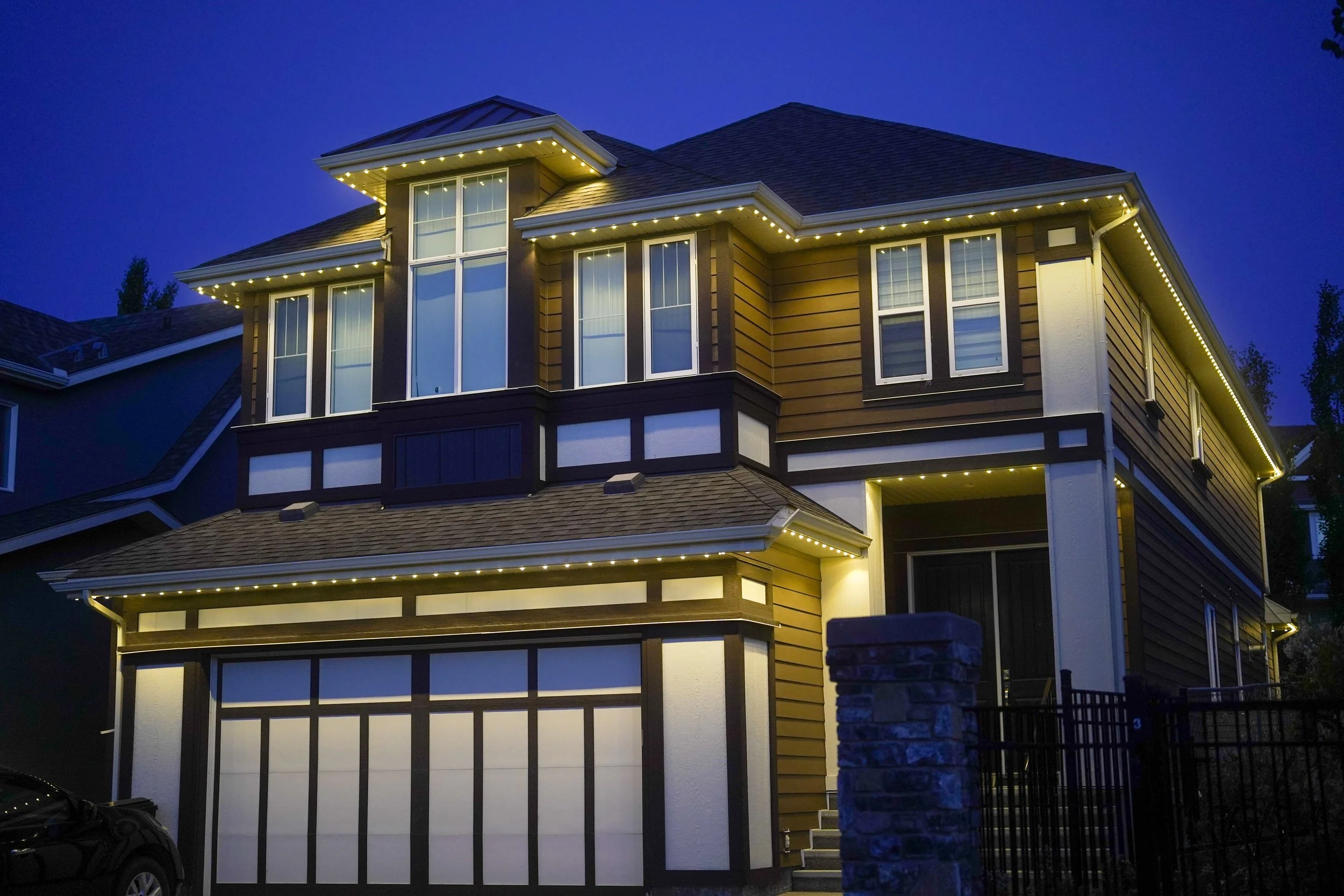 Modern multi-story house with exterior lighting and large windows at dusk.