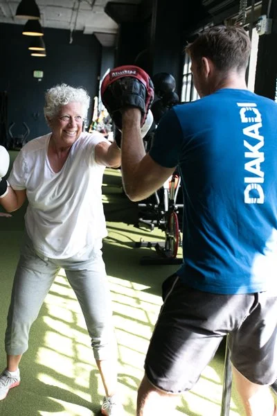 Senior female working on upper body strength with a male trainer.