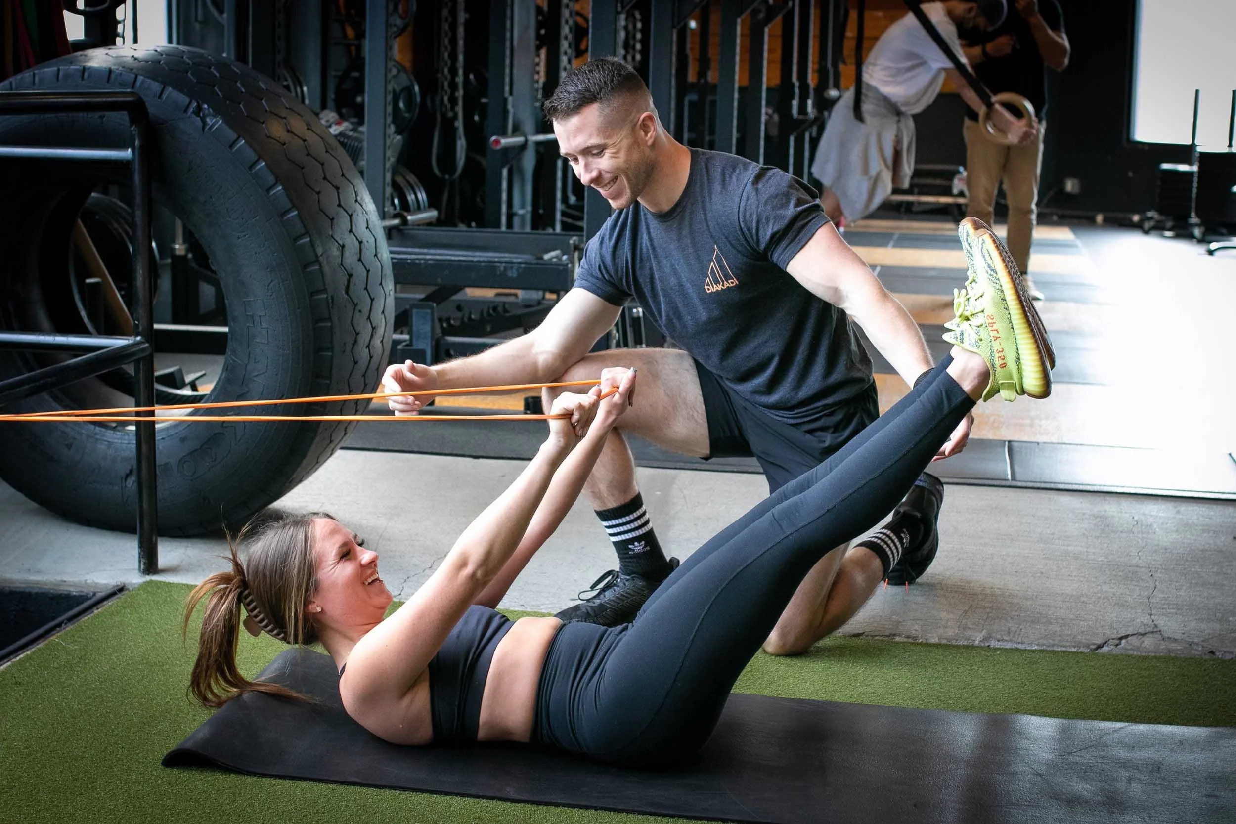 Male personal trainer assisting a women with resistance leg lifts.