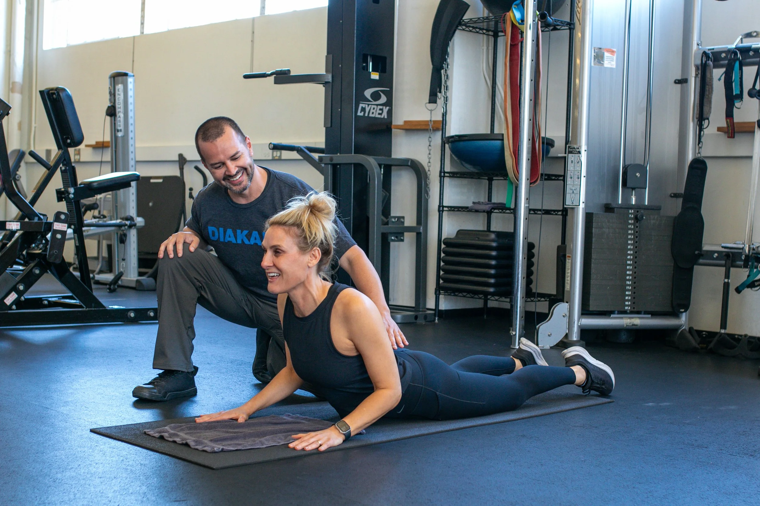 Male personal trainer working with female client on core strength exercise.