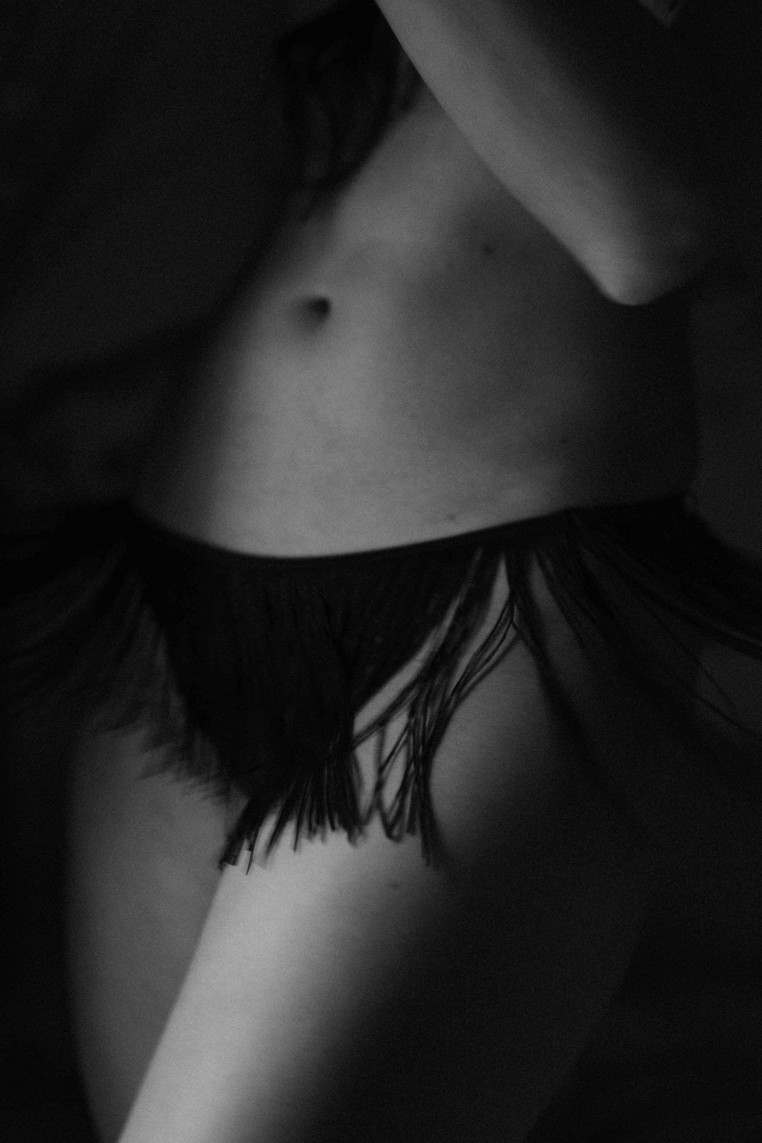 A black and white close-up photo of a person's lower torso and upper thighs, with wet hair covering part of their body.