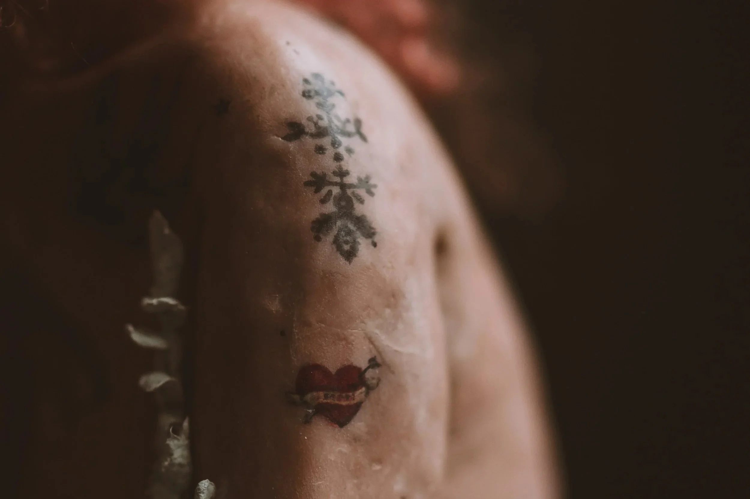 Close-up of a person's skin with a tattoo, partially obscured by water droplets or tears.