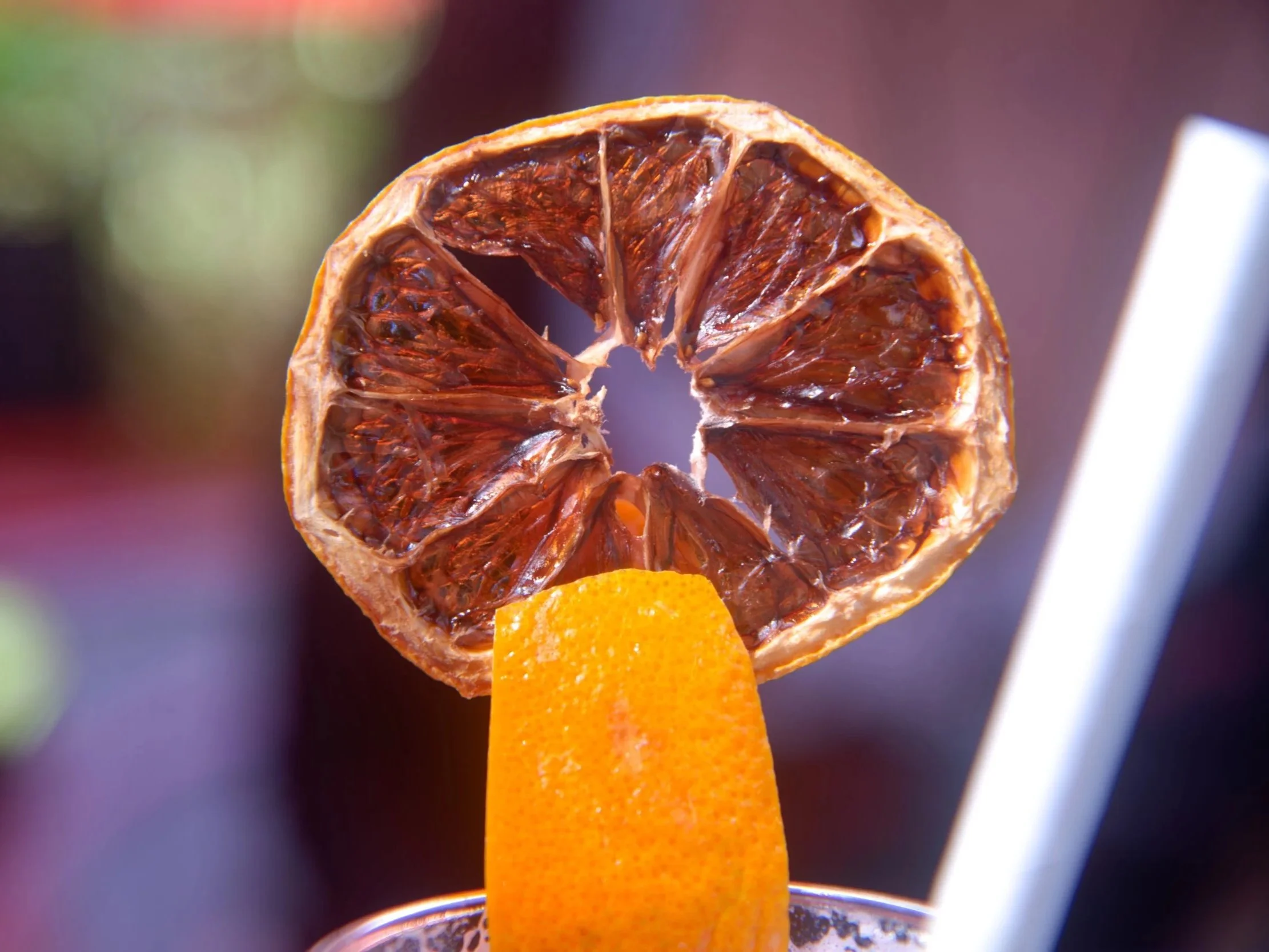 Un fruit déshydraté de citron ou d'orange placé sur un support orange, avec une paille blanche à côté. - Photographe packshot à La Réunion