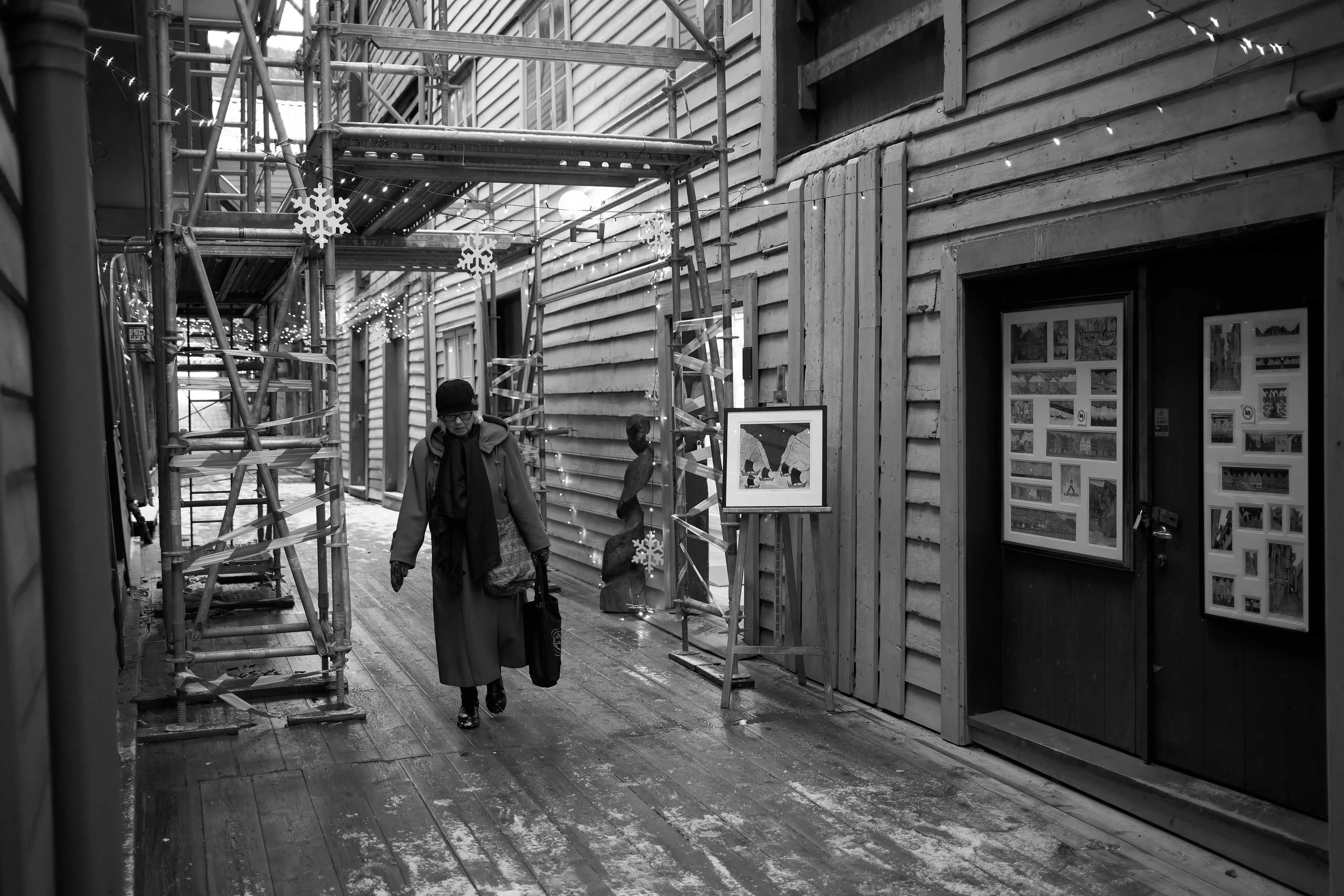 Scène en noir et blanc d’une femme marchant dans une ruelle en bois sous des échafaudages — Photographe lifestyle à La Réunion
