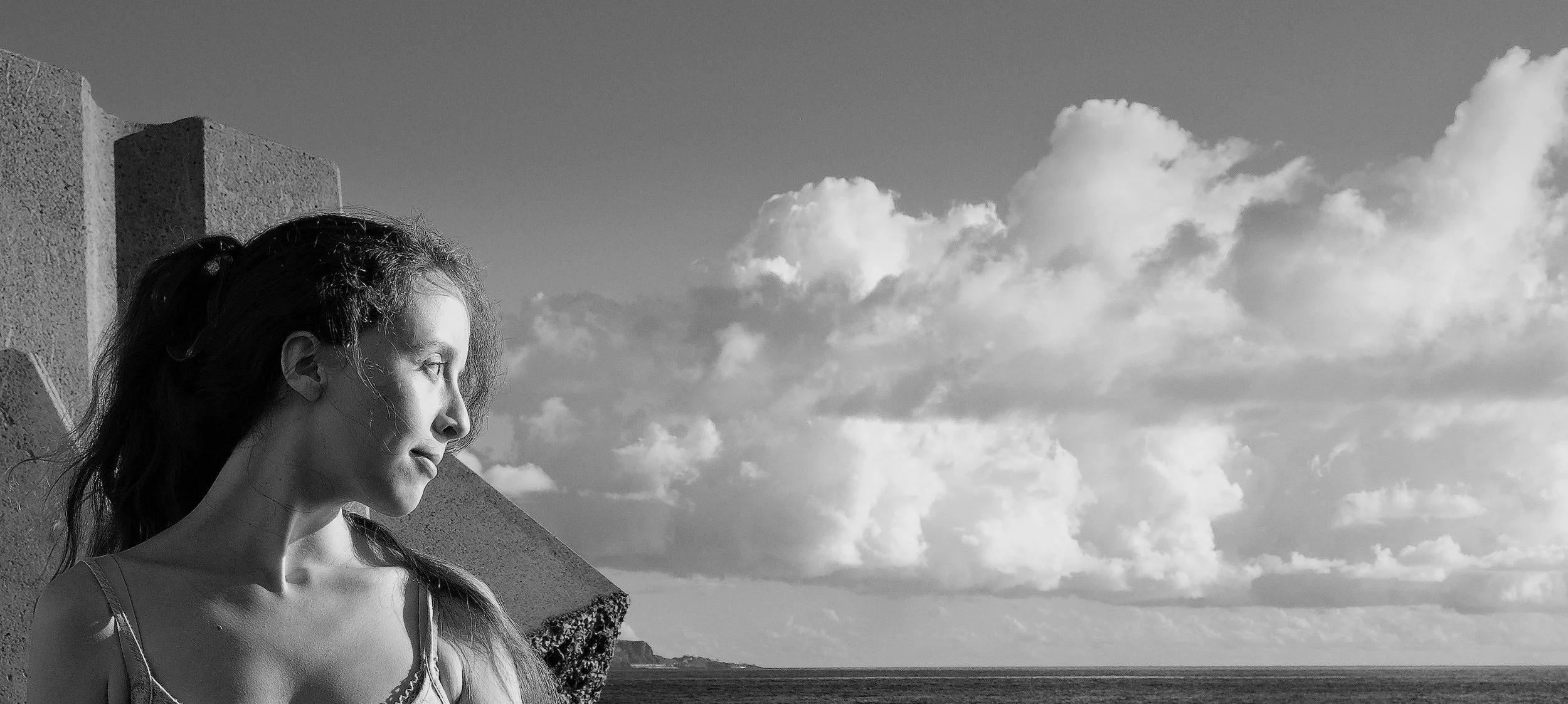 Portrait en noir et blanc d’une jeune femme de profil face à la mer et aux nuages — Photographe lifestyle à La Réunion