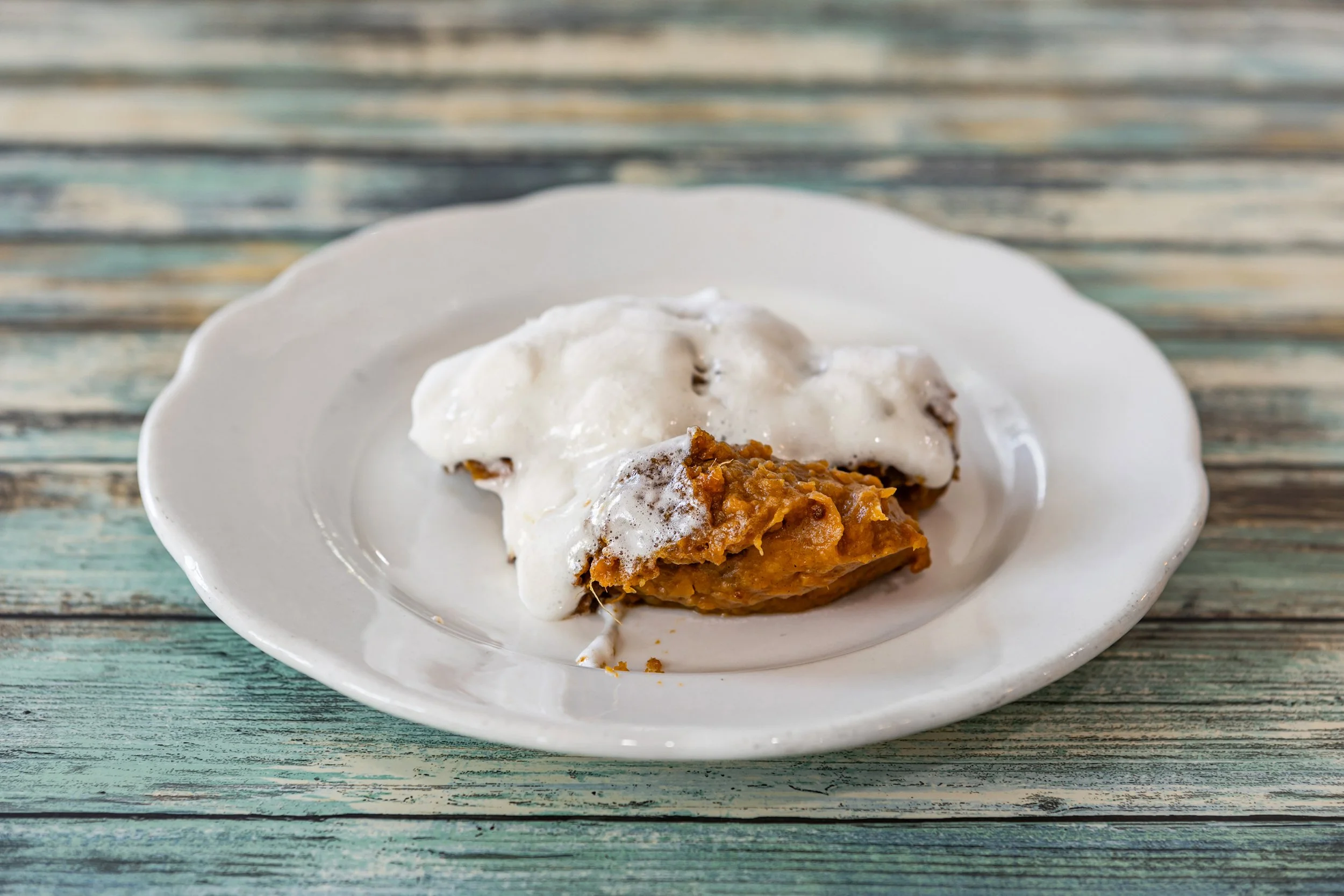 Slice of sweet potato casserole topped with marshmallows on a white plate.