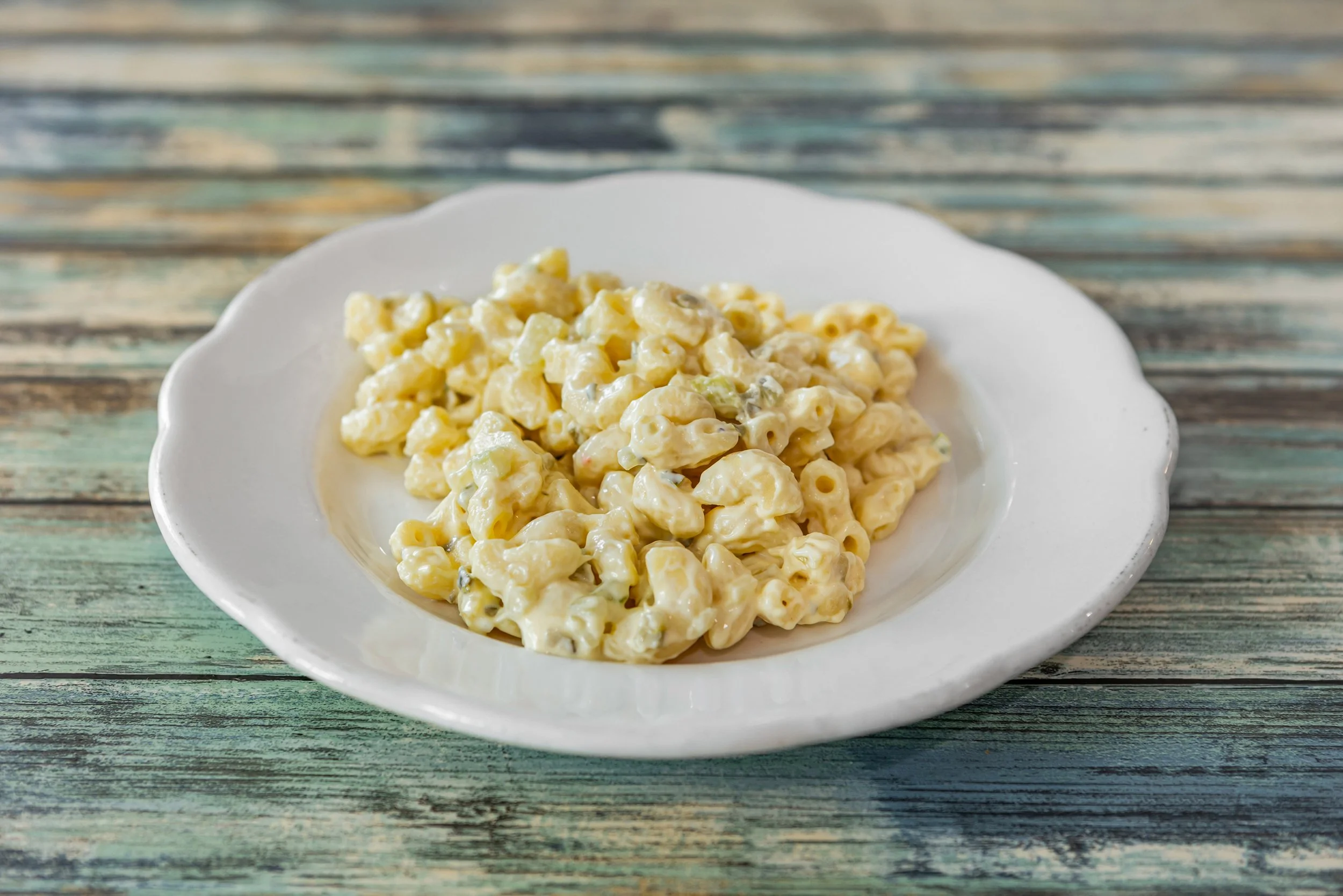 Creamy macaroni and cheese on a white plate on a rustic wooden table.