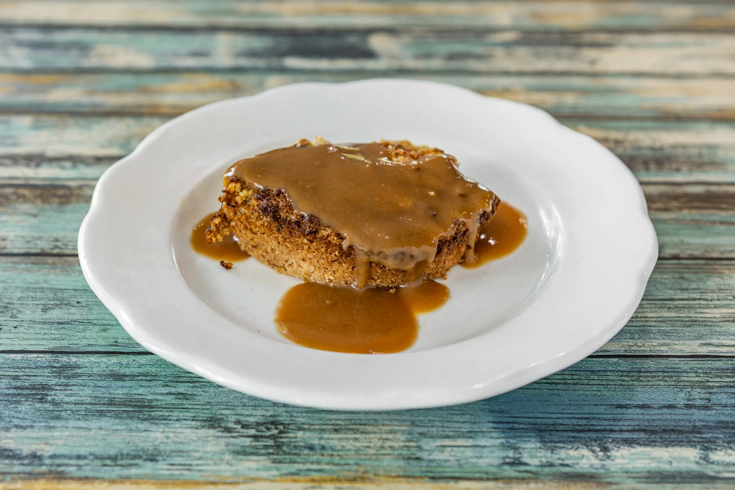 Slice of pumpkin or sweet potato pie with brown caramel sauce on a white plate