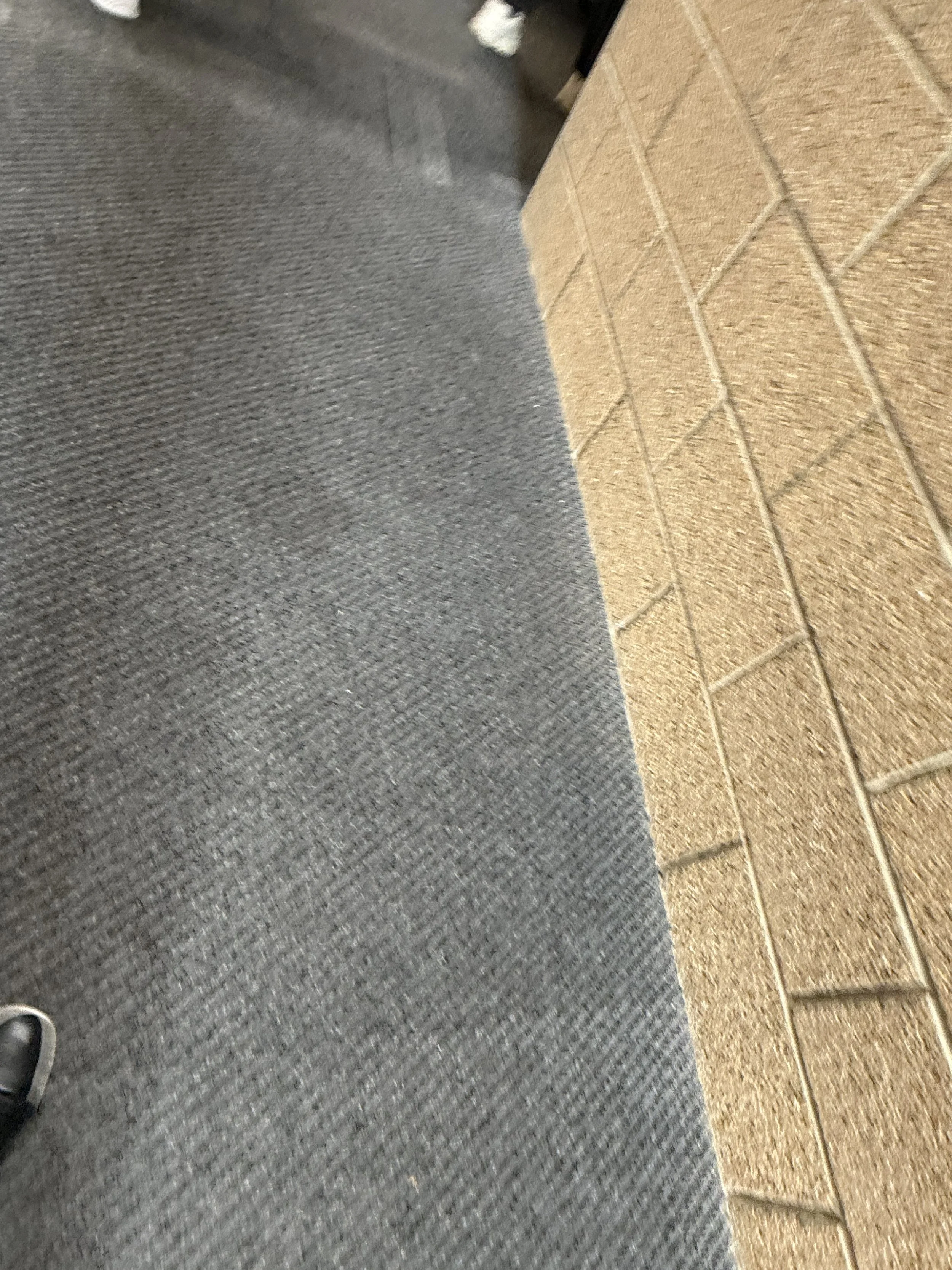 Close-up of a red brick wall and a gray carpeted floor.