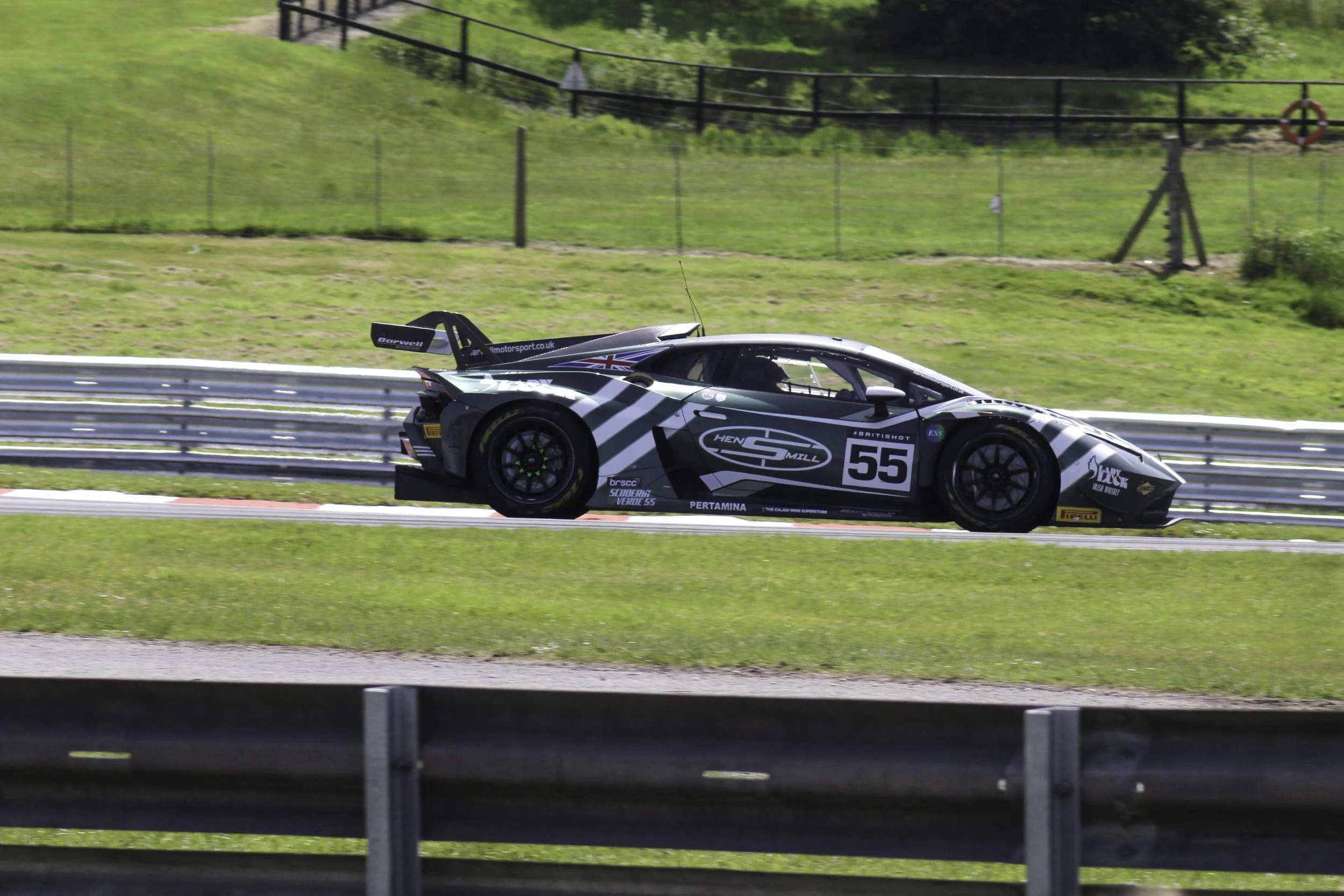 A race car on a track with green grass and trees in the background.
