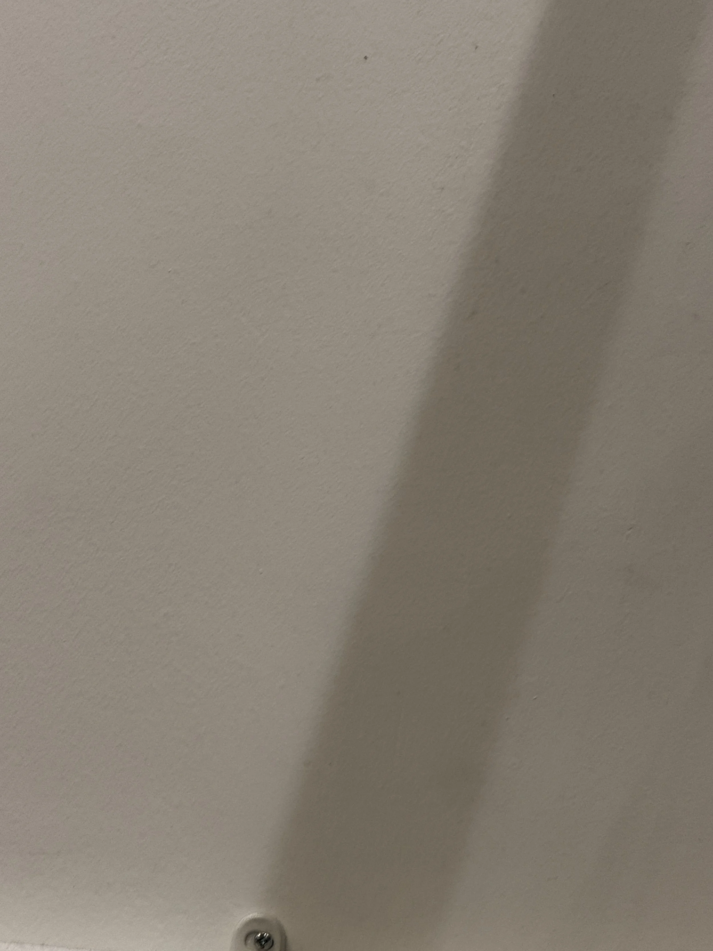 A white ceiling with a ceiling light fixture and a shadow cast on the right side.