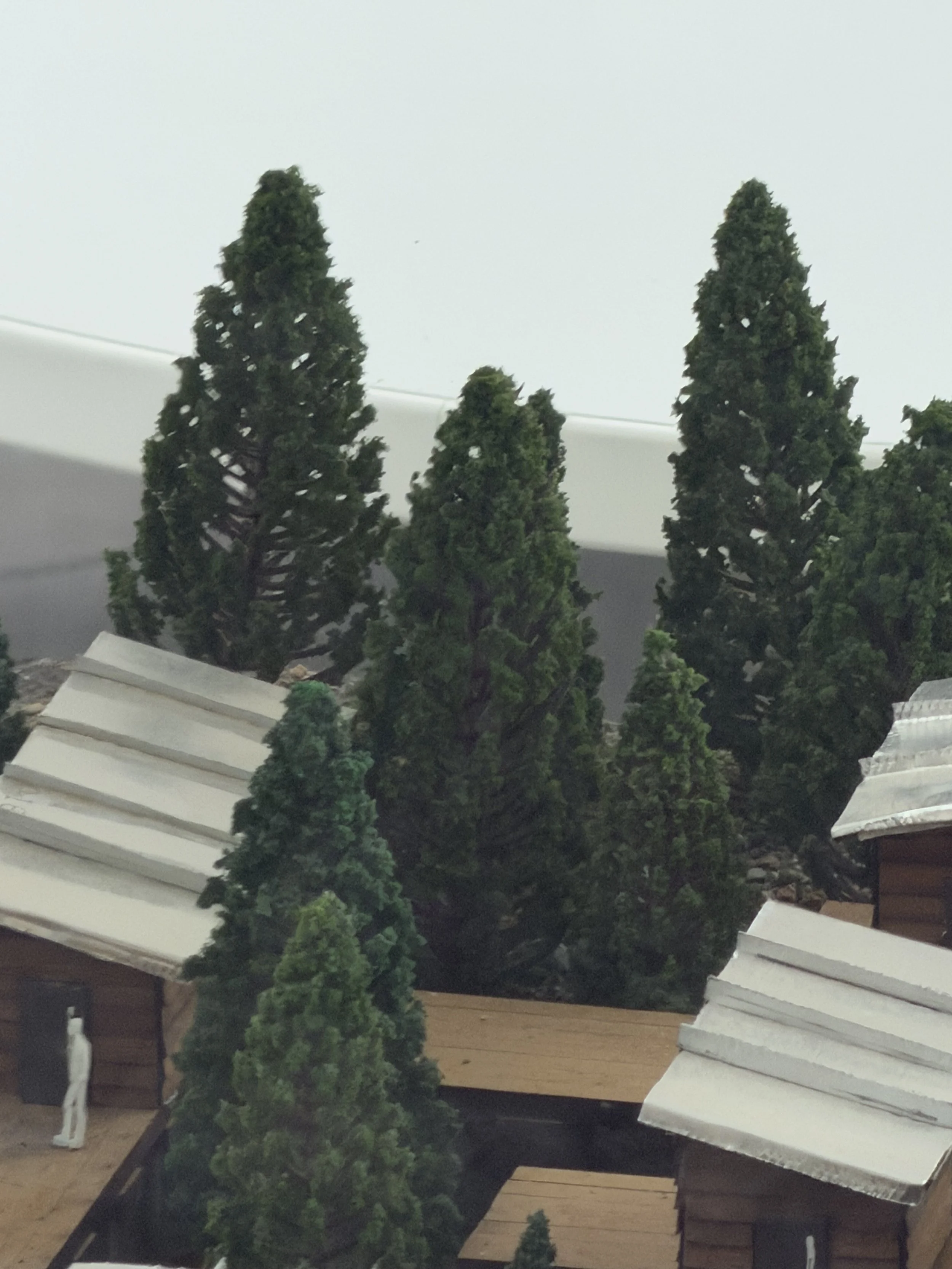 Miniature model trees and buildings with snow-covered roofs as part of a winter village scene.